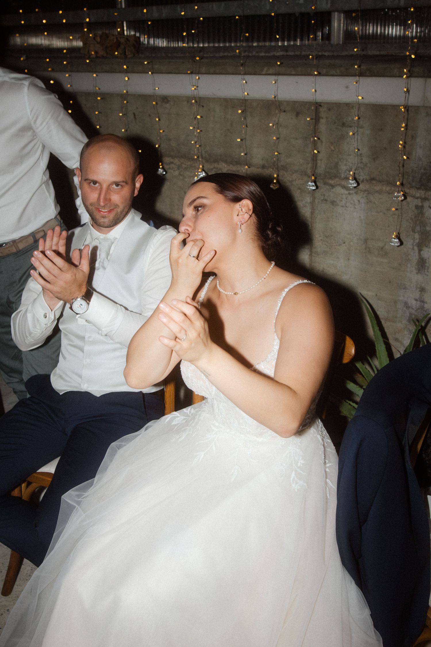 Bride in white gown and guest share emotional moment during wedding reception.