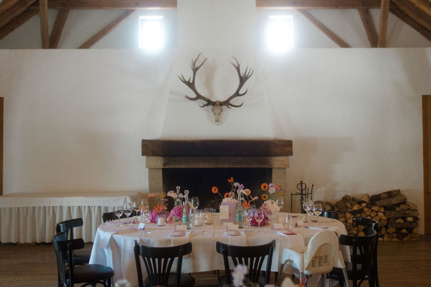 Rustic dining room with antler mount above fireplace and table settings for wedding reception.