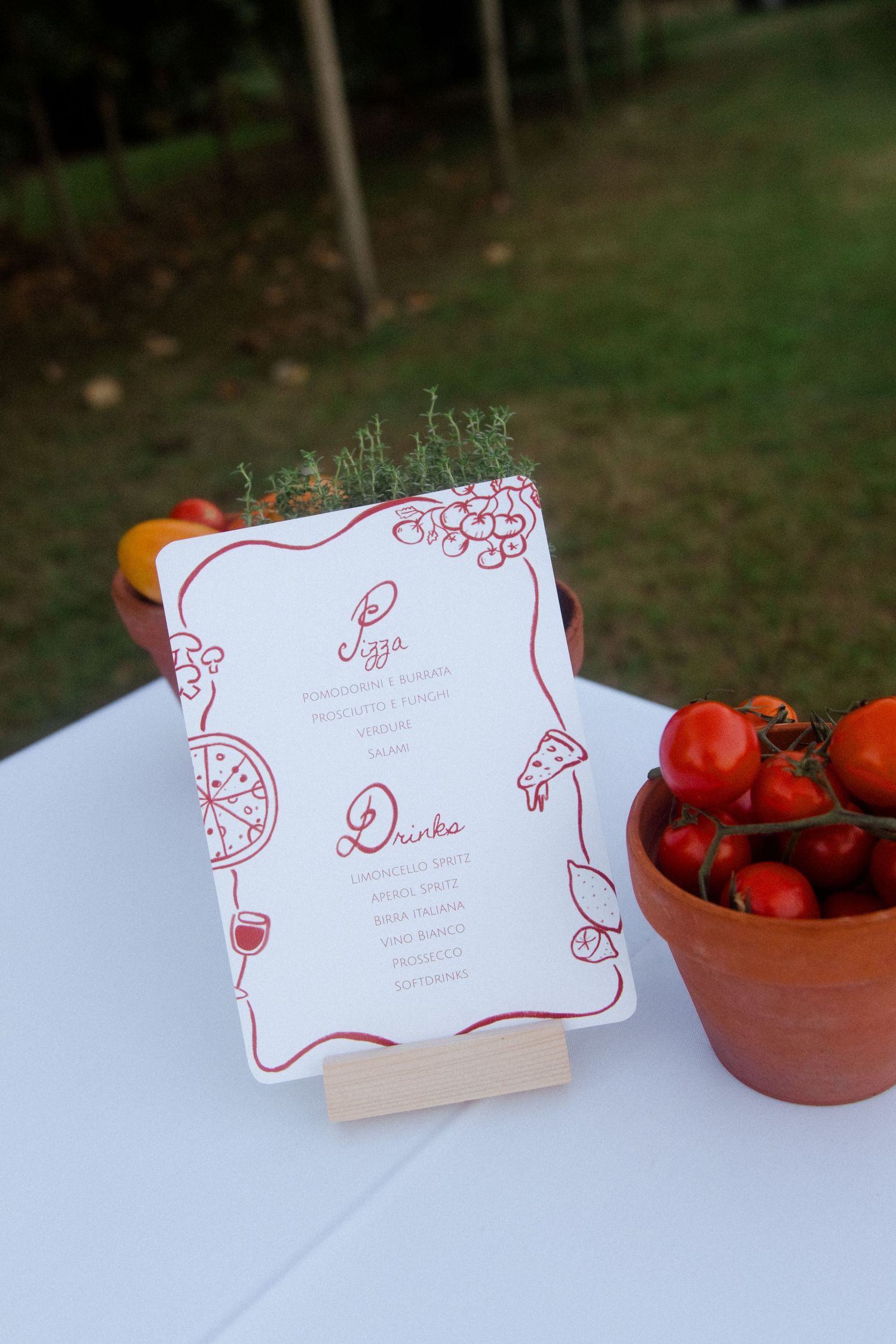 Wedding menu card with red decorative border next to bowl of fresh tomatoes.