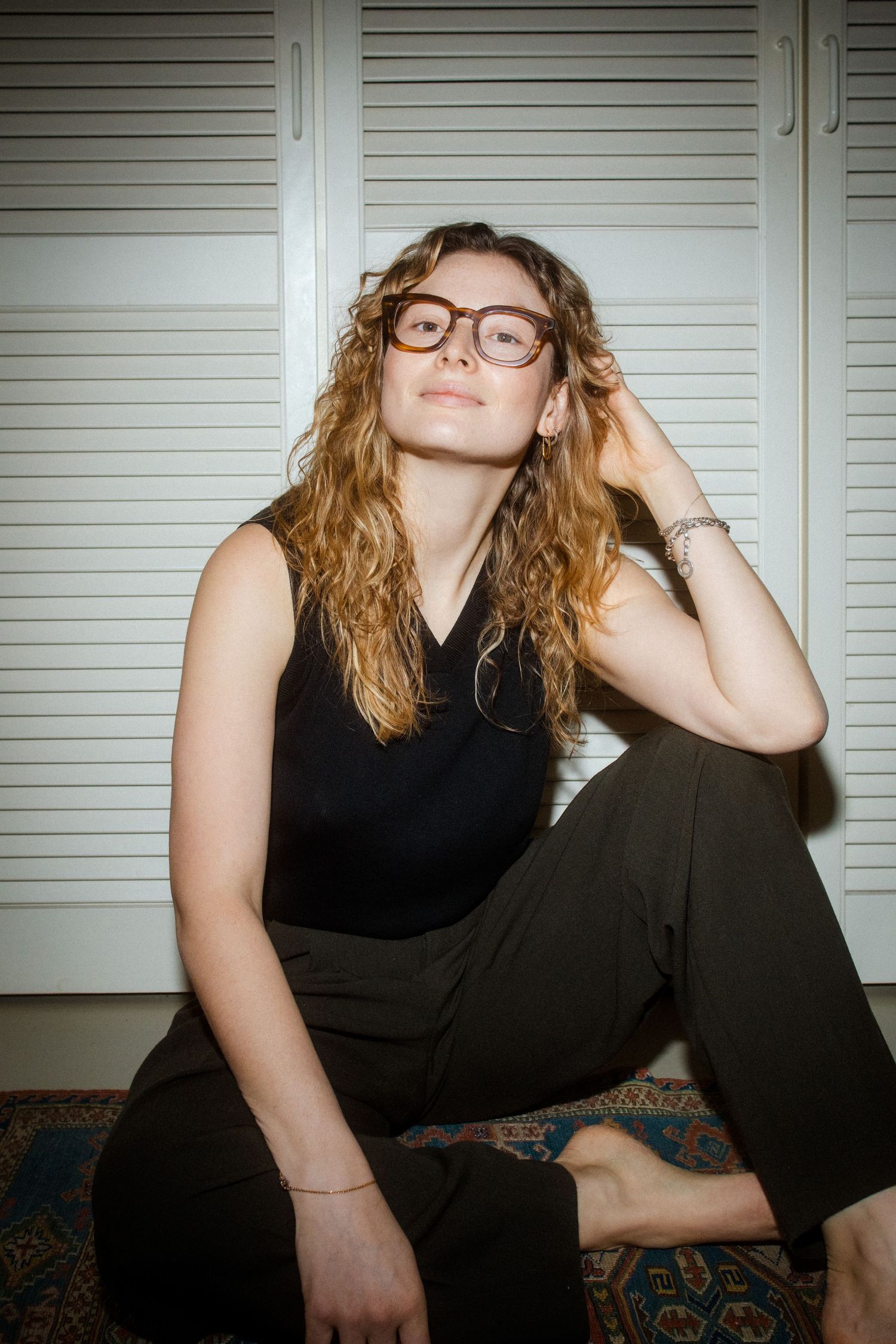 A series of casual portraits showing someone in black attire lounging on a patterned couch against white shutters.