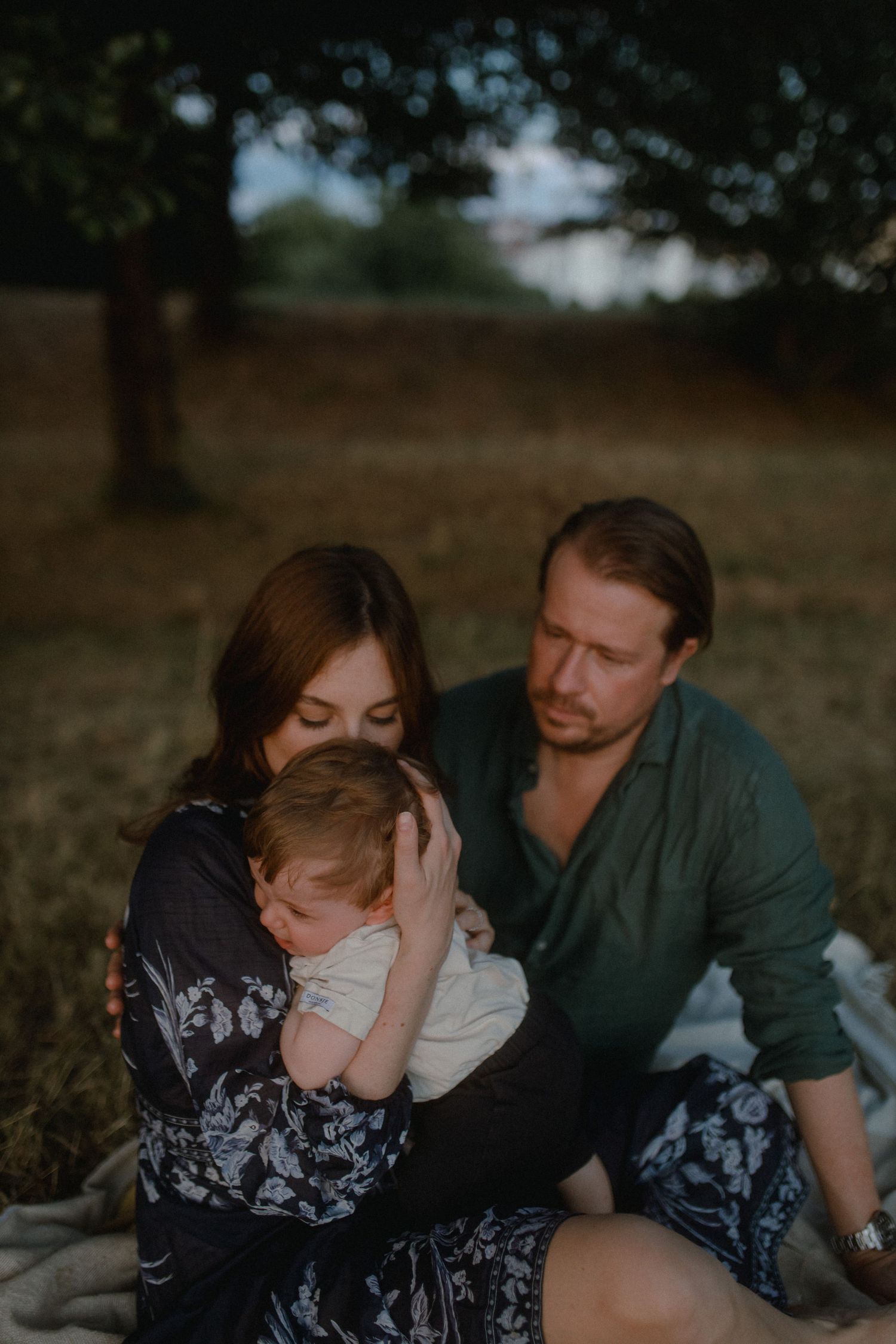 A family shares intimate moments together while relaxing outdoors in a natural setting.