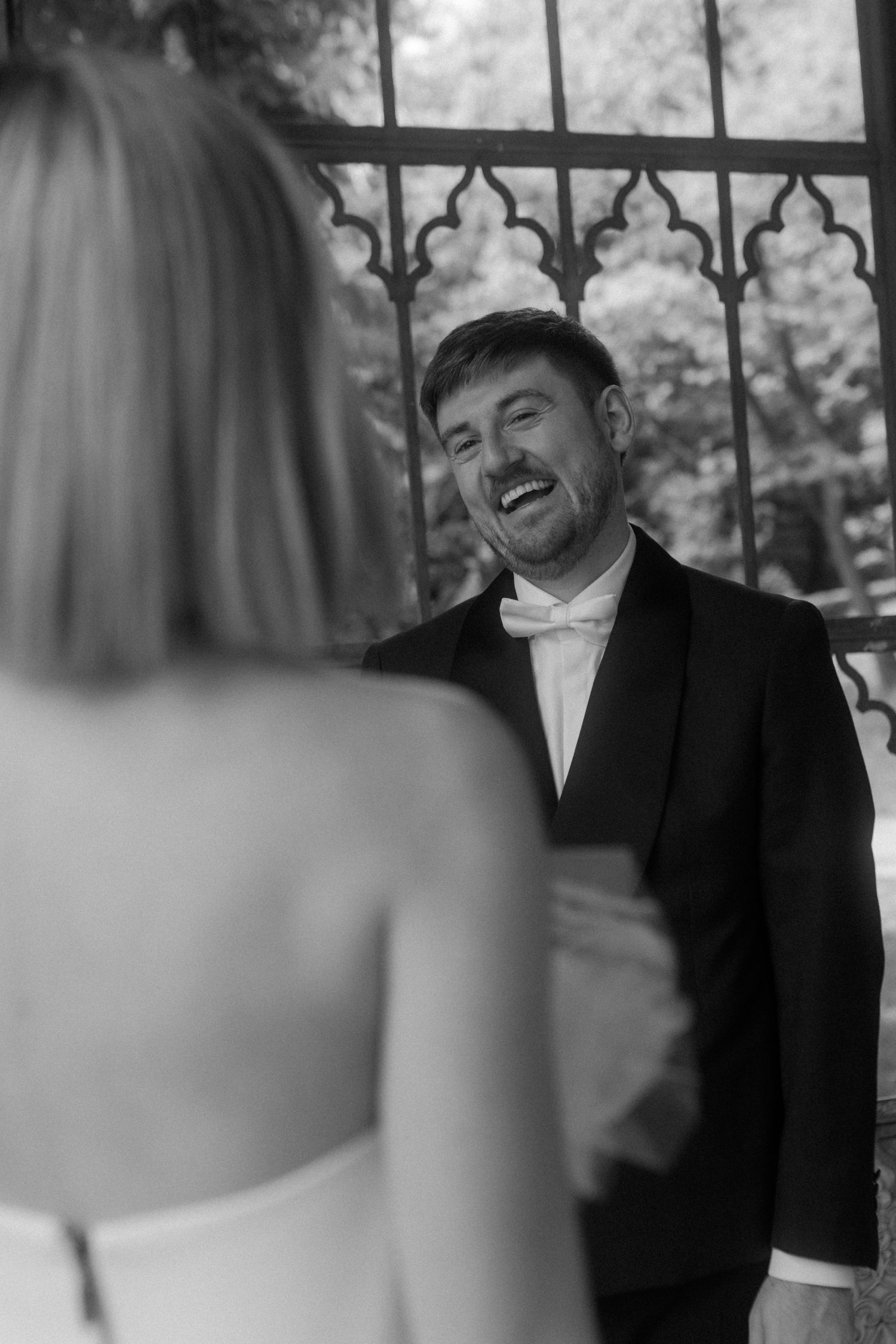 Black and white portrait showing joyful laughter during a wedding ceremony.