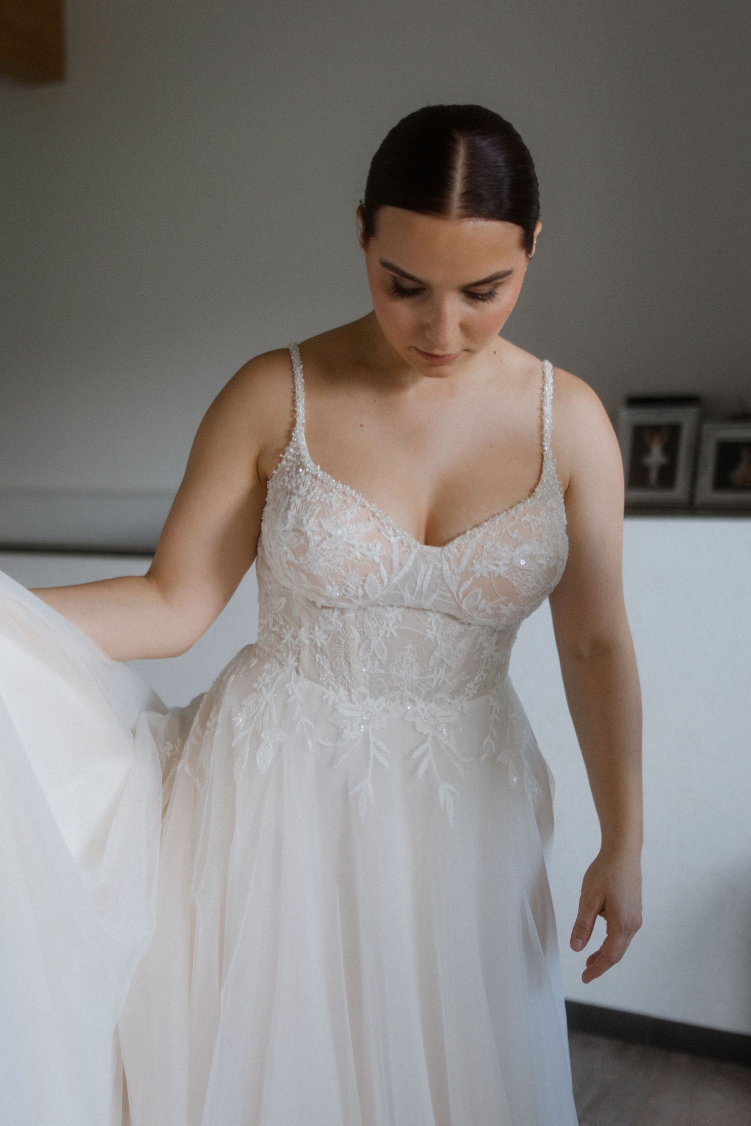 Close-up of delicate lace wedding dress with spaghetti straps and flowing tulle skirt.
