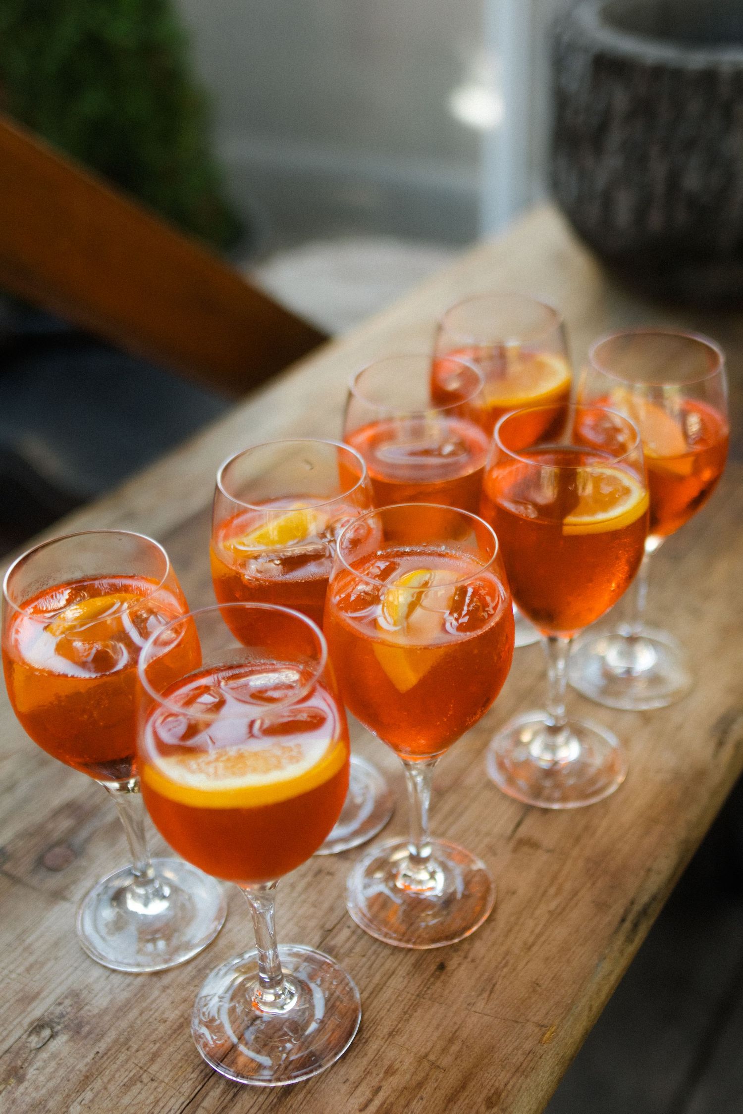 Orange cocktails garnished with citrus slices arranged on a rustic wooden surface.