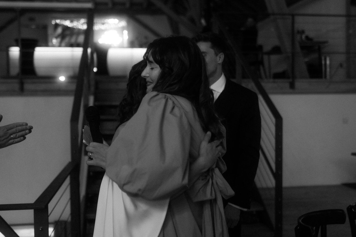 Black and white photo of people during evening event in rustic indoor setting.