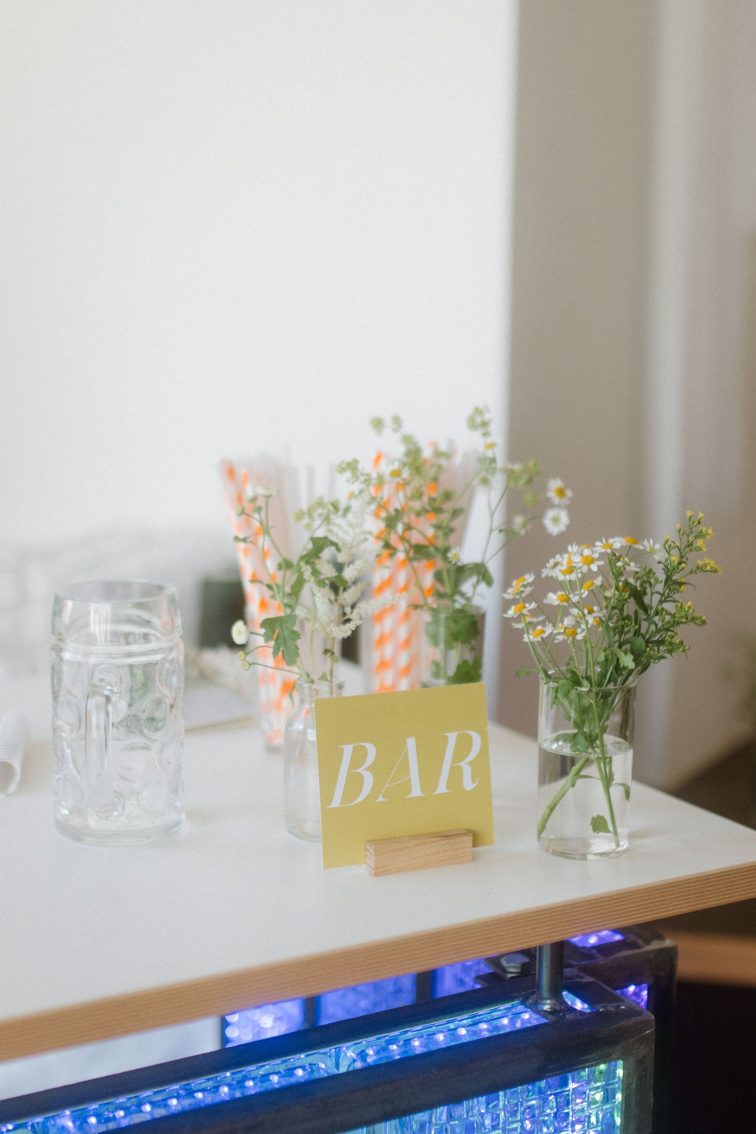 Bar setup with delicate floral arrangements and decorative signage on white counter.