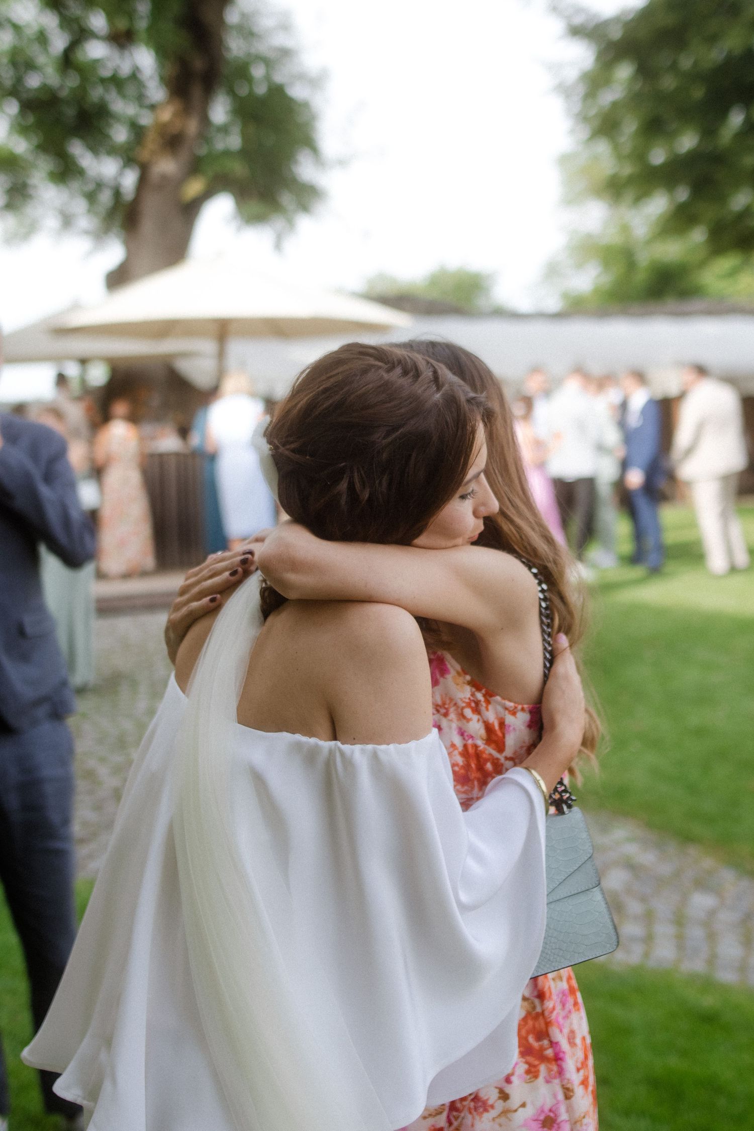Emotional embrace between guests at outdoor garden wedding reception.