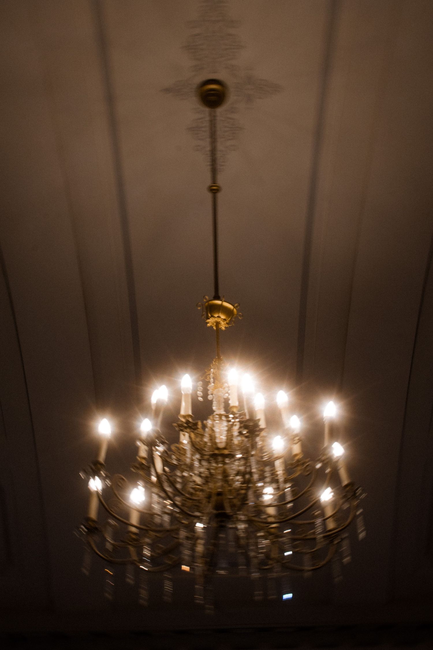 Elegant crystal chandelier with multiple tiers of lights illuminating a dark room.
