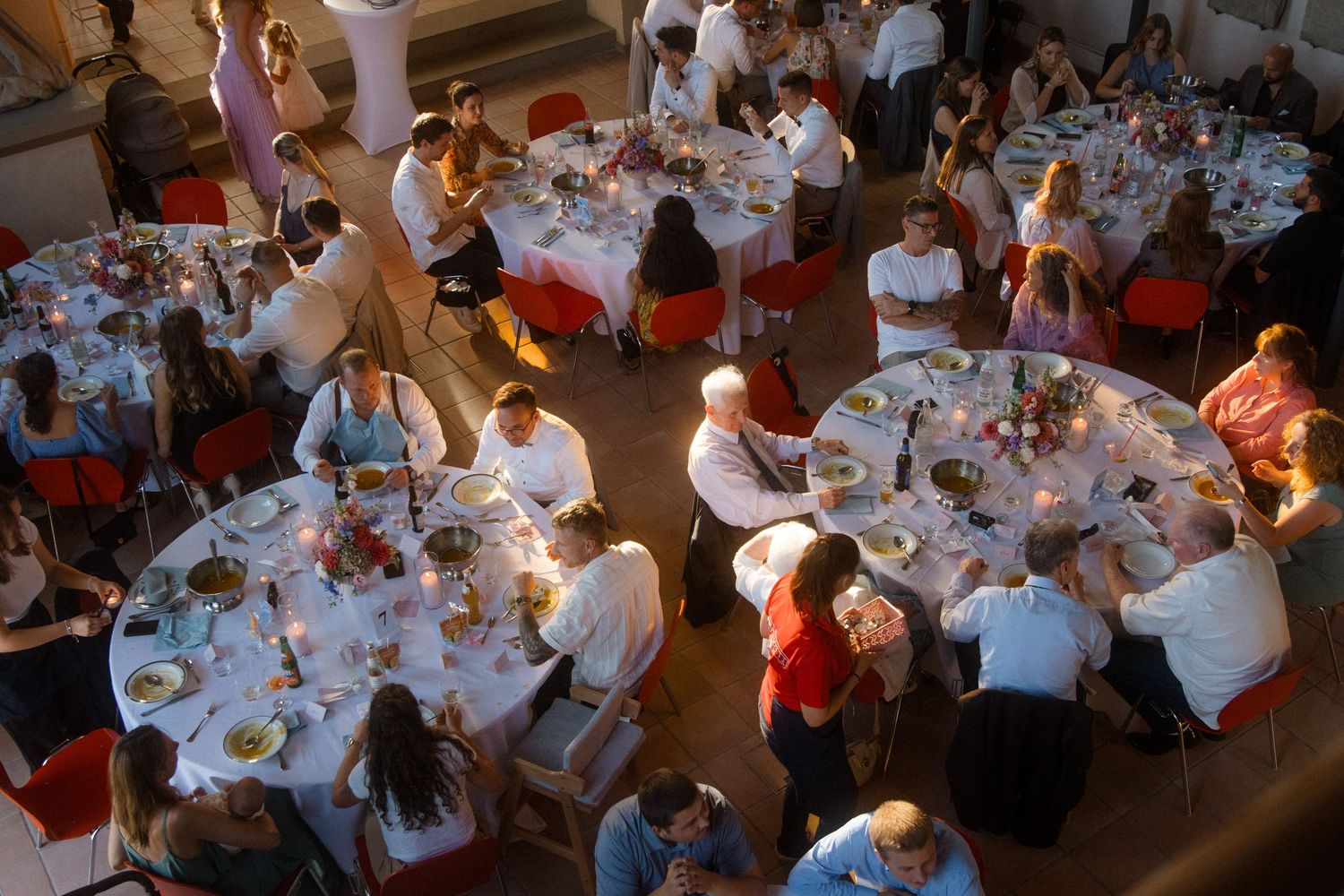 Overhead view of wedding reception with decorated tables and dining guests.