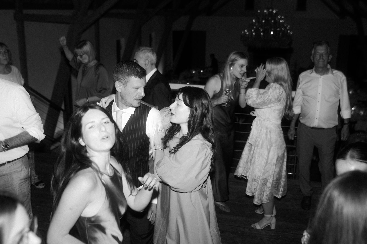 Black and white photo of wedding guests dancing and celebrating on the dance floor.