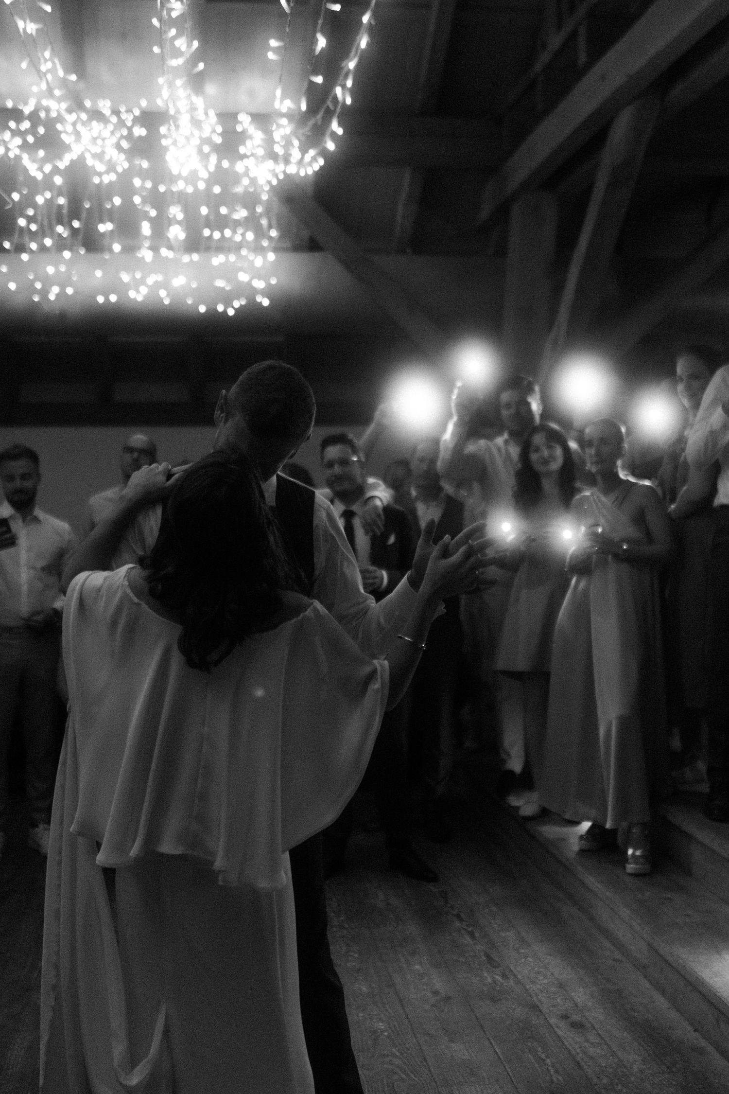 A couple's first dance under twinkling lights at their wedding reception.
