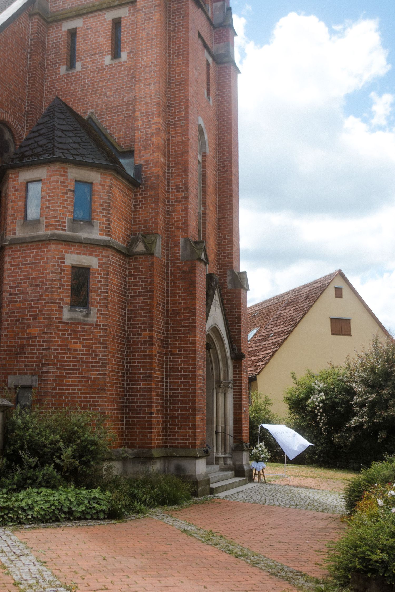 Side view of red brick church architecture with adjacent yellow building.