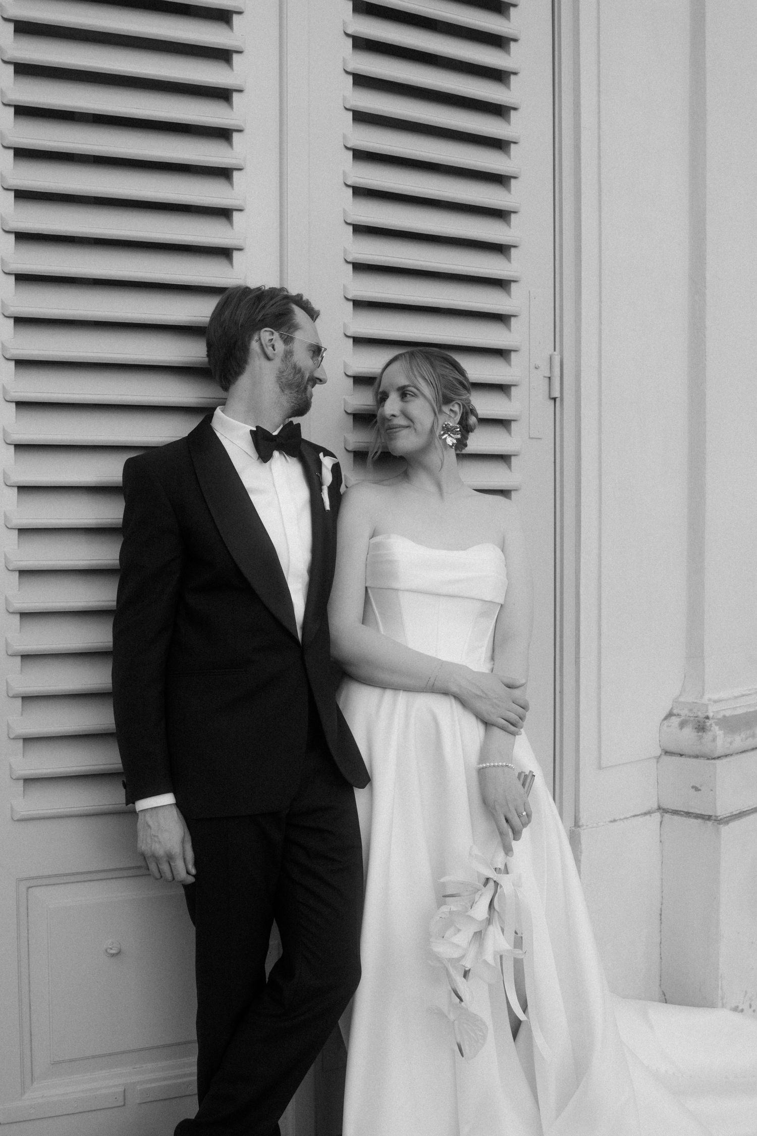 Black and white wedding portrait against vintage shuttered doors.