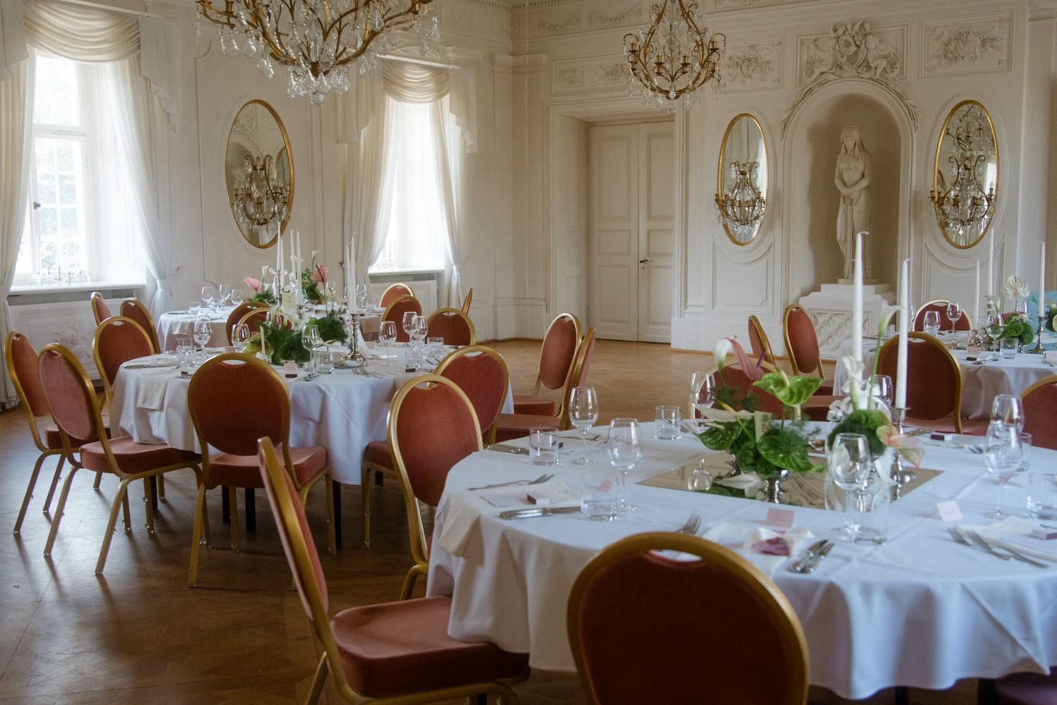Elegant wedding reception room with crystal chandeliers and ornate white wall details.