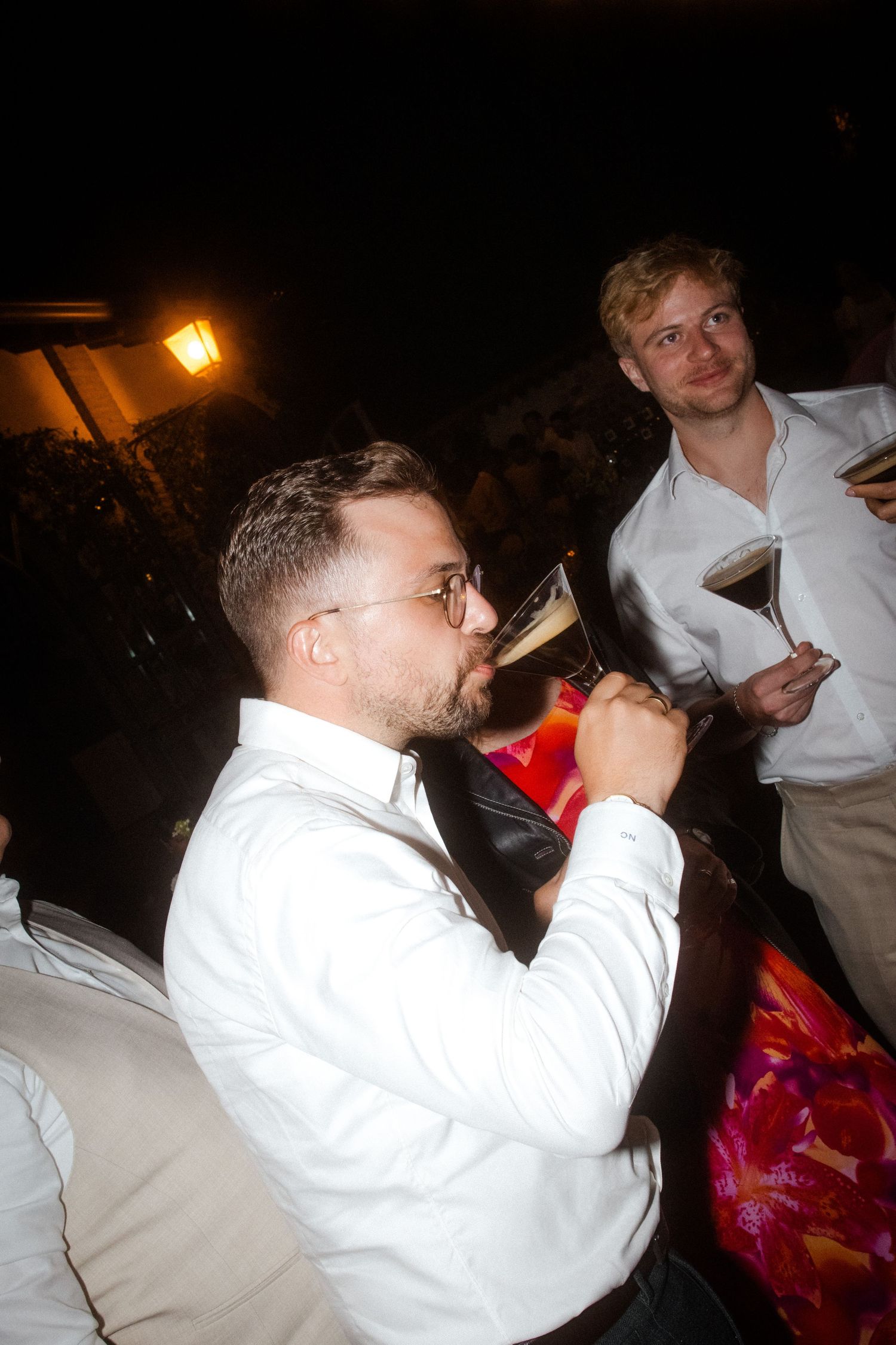 Guests enjoying drinks and celebrating at nighttime wedding reception.