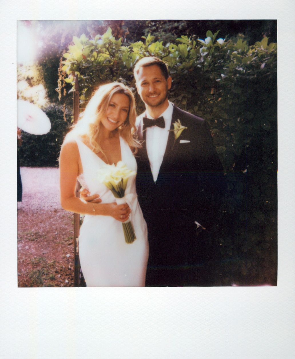 A couple in formal wedding attire posing together outdoors.