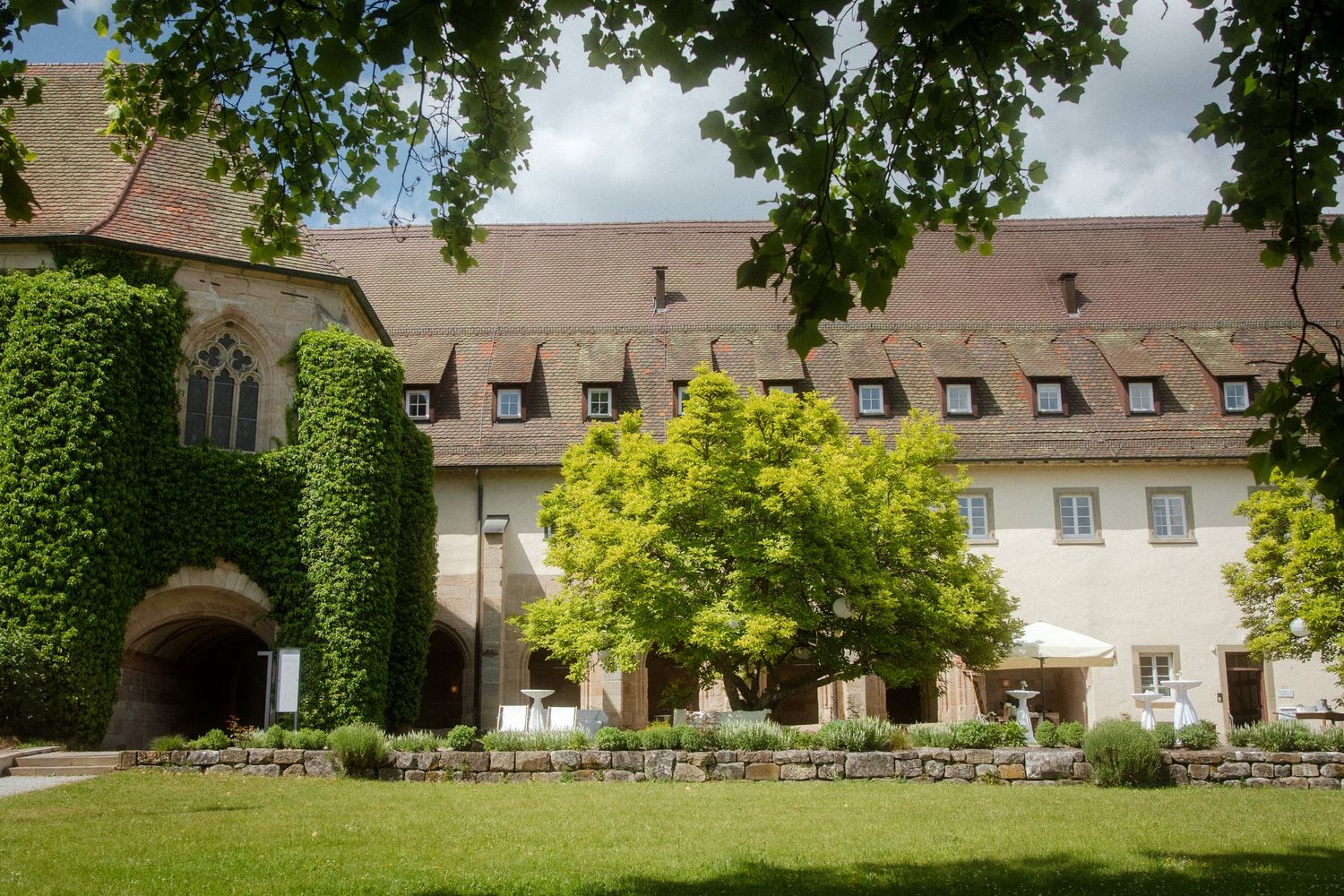 Historic ivy-covered building with manicured lawn and outdoor seating area.