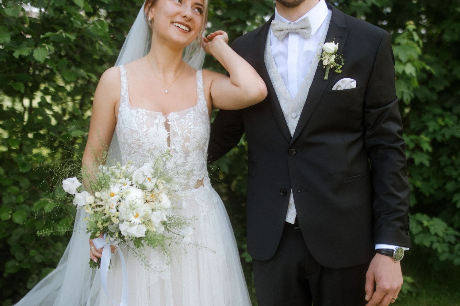 Bride and groom laugh together during outdoor wedding photo session.