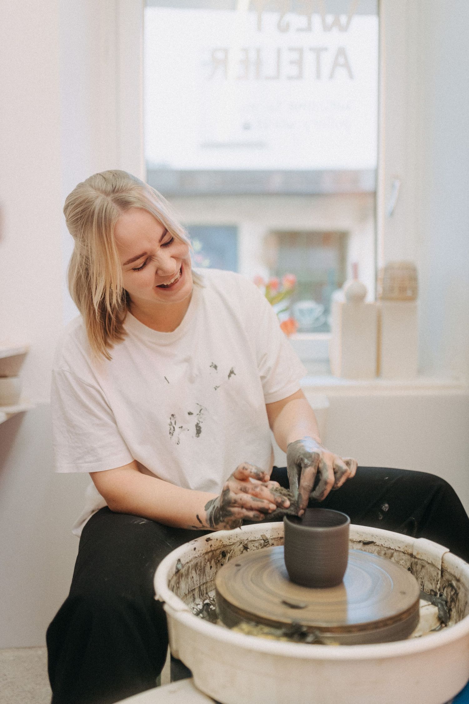 Artist working with clay on a pottery wheel in a bright studio space.