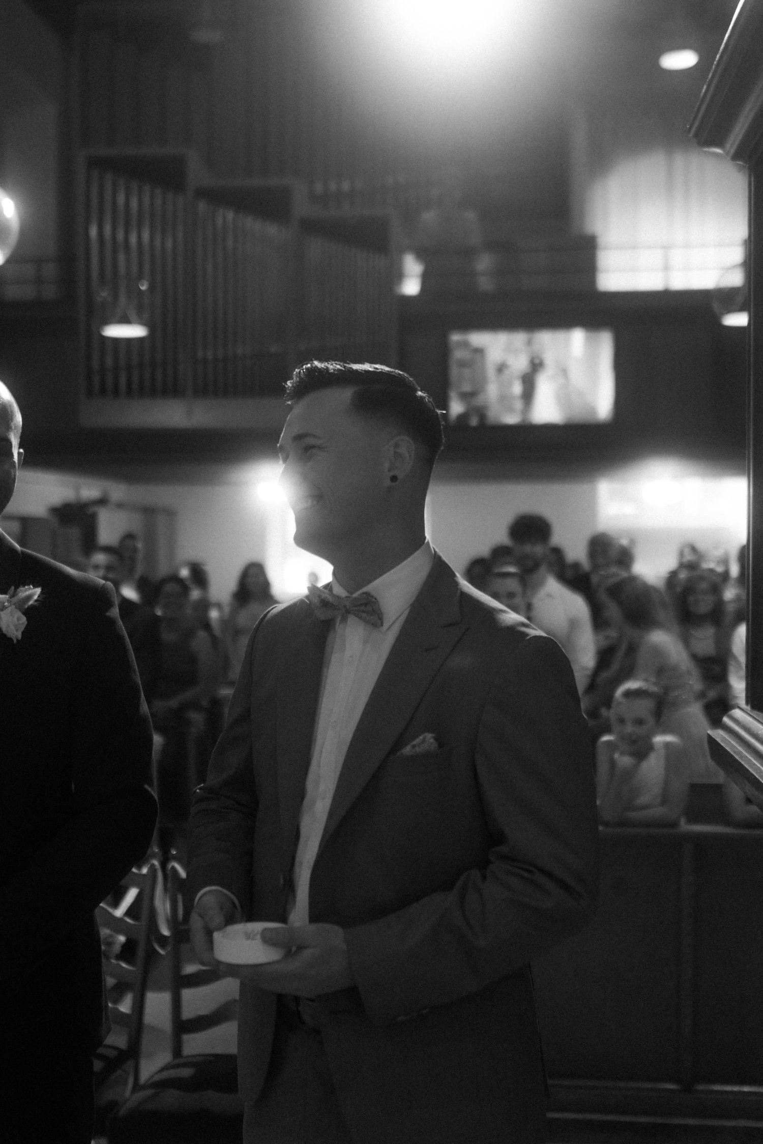 Guest stands in formal attire during evening wedding ceremony.