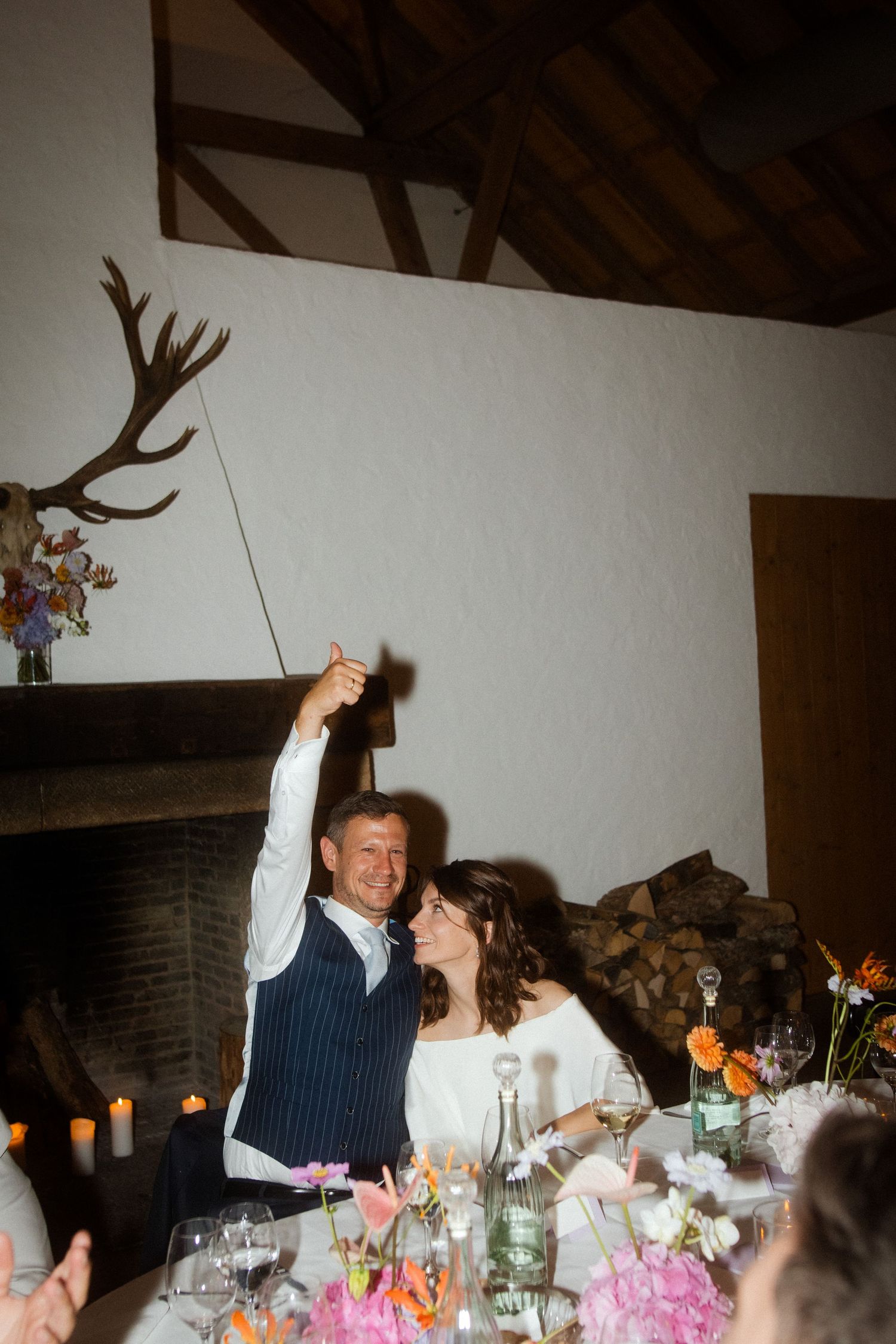 Wedding celebration moment with rustic wooden beams and antler decor on wall.