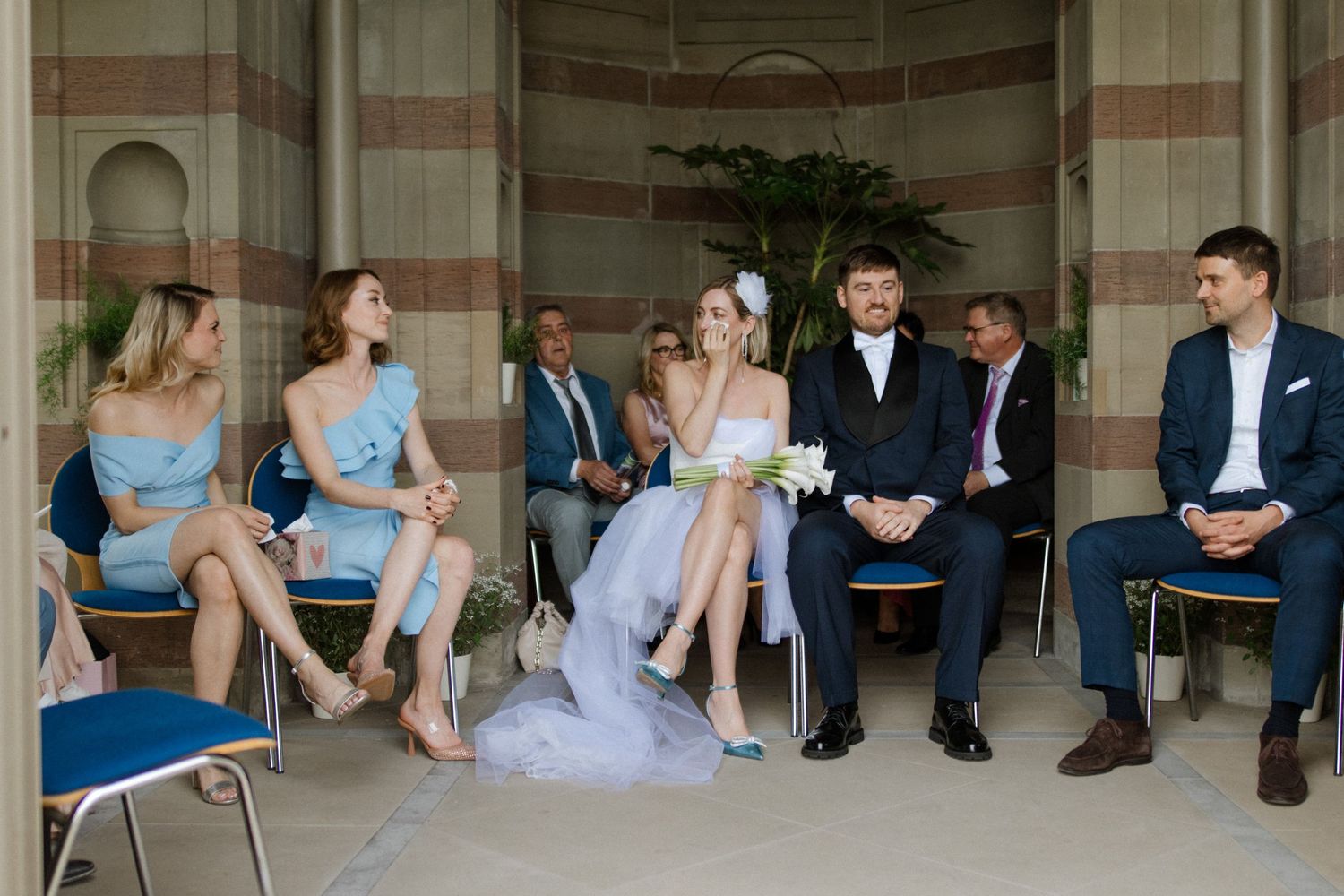Wedding party seated in an ornate colonnade with striped architectural details.