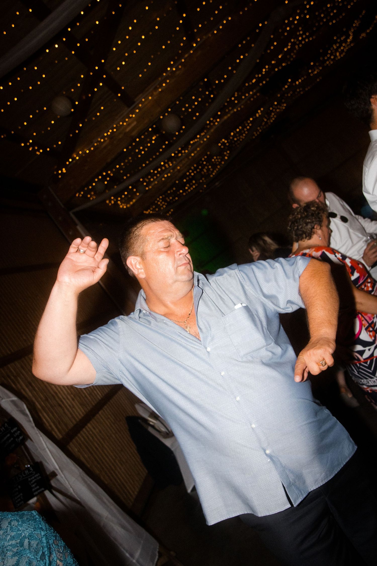 Person dancing enthusiastically under twinkling lights at a nighttime celebration.