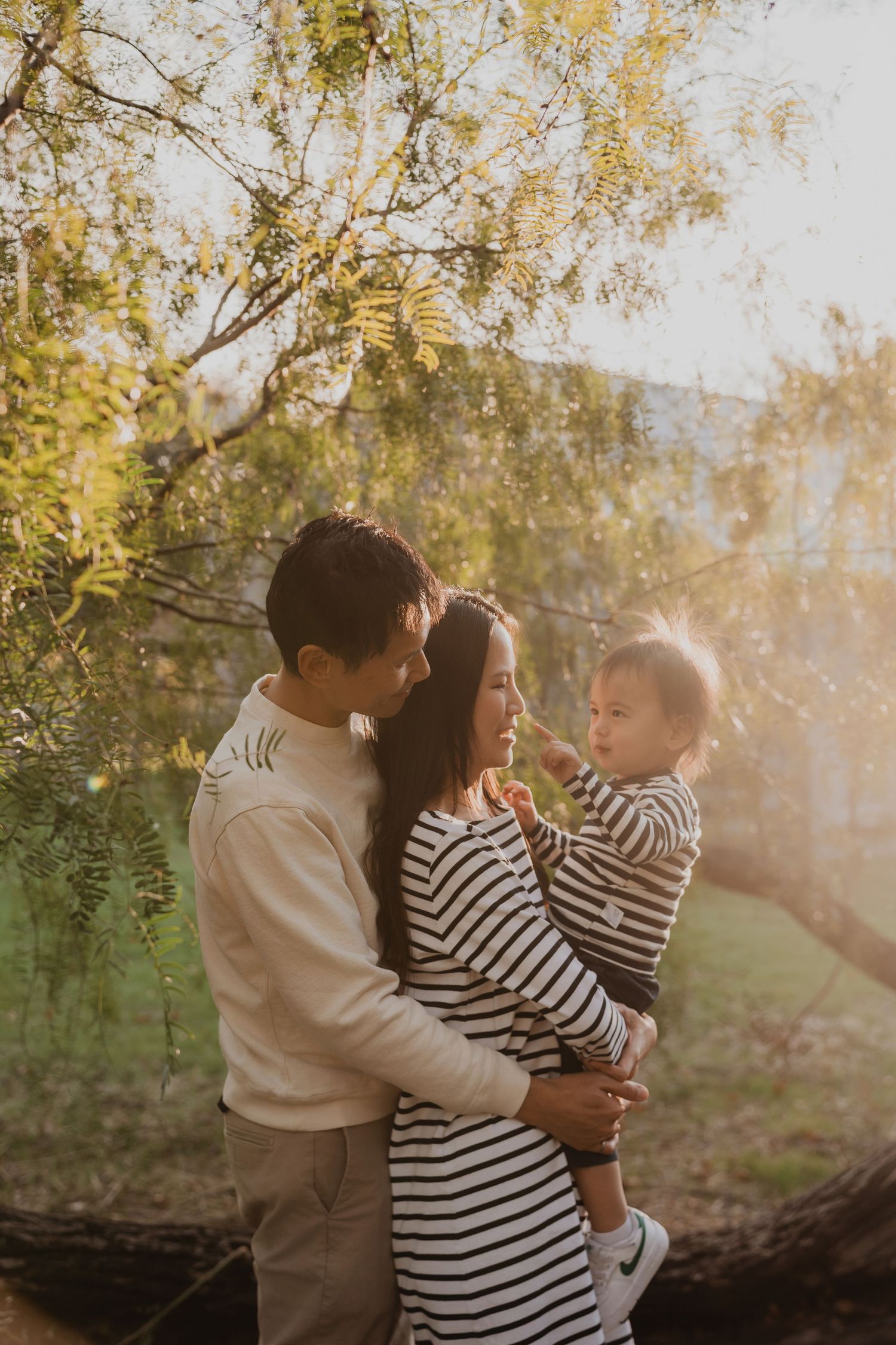 A family shares a tender moment together outdoors during golden hour sunlight in a natural setting.