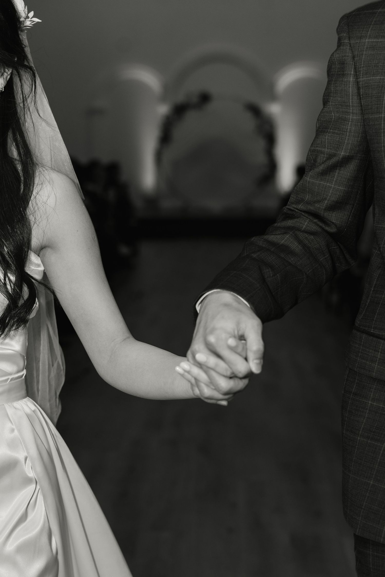 Black and white photograph showing two hands clasped together during a romantic dance at a formal event.