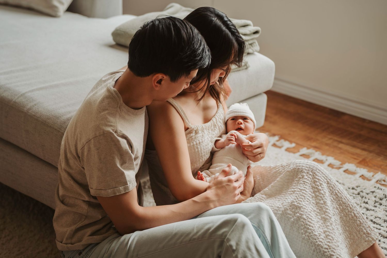 Intimate family moment on white couch in sunlit living room.