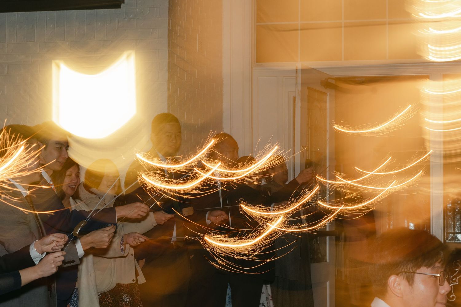 Long exposure photograph showing golden light trails and motion blur in an indoor setting during a celebration or event.