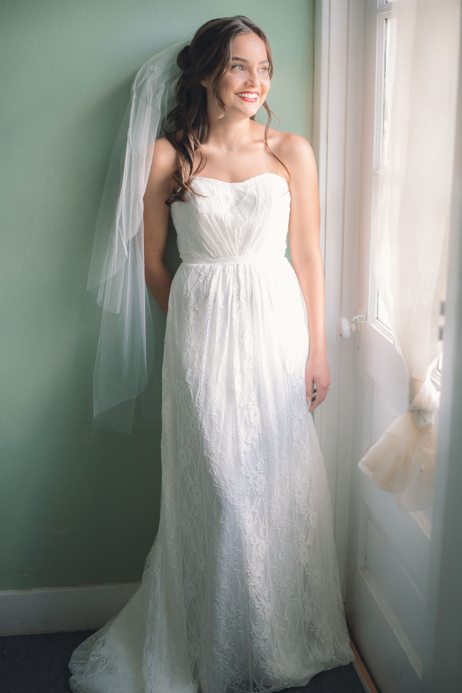 Soft light from a nearby window shines an instant glow on the bride, lighting up her bridal portrait session in true to color + light & airy