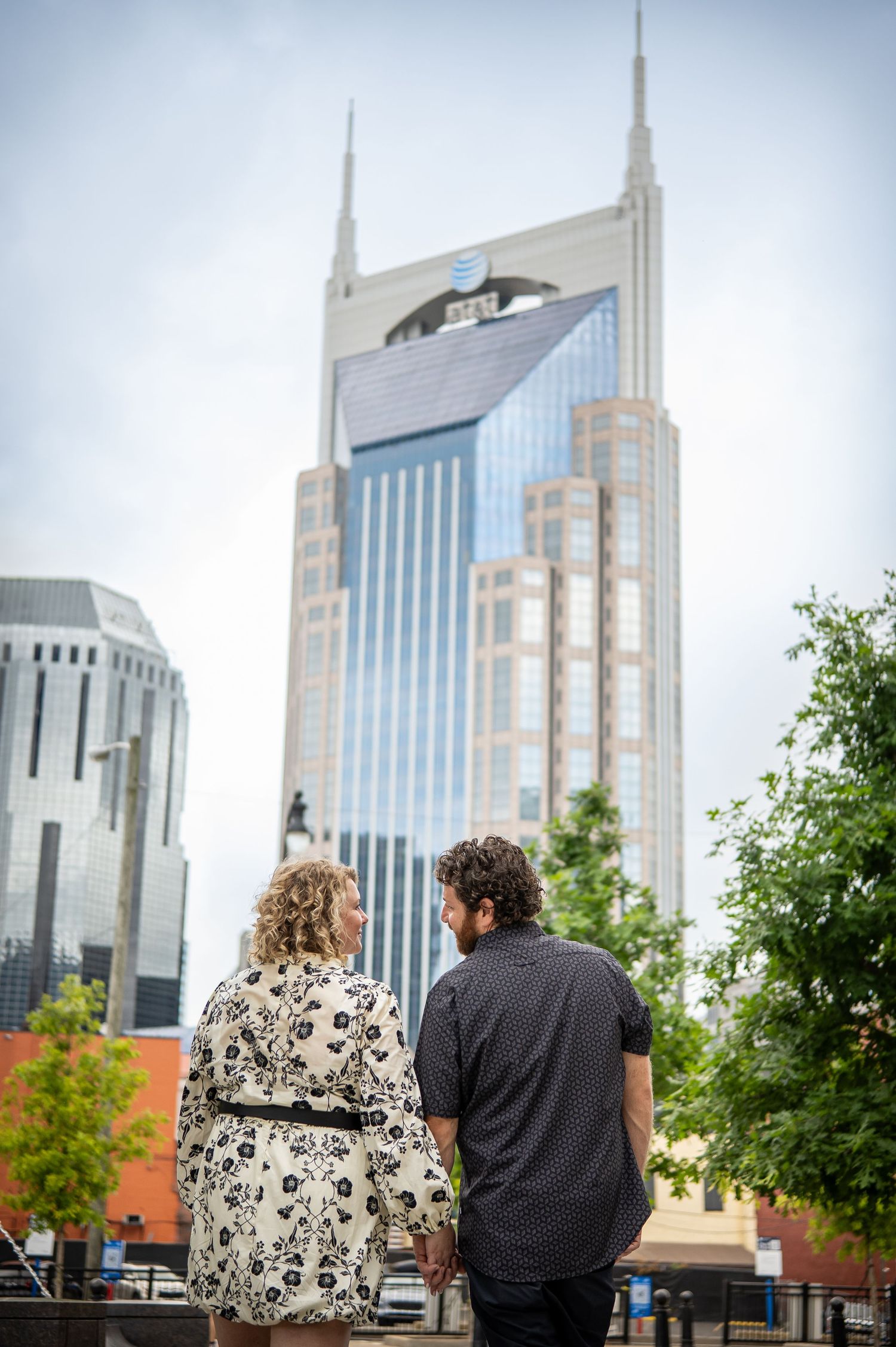 Couple holding hands gazing at the AT&T Batman Building skyscraper in downtown Nashville, Tennessee.