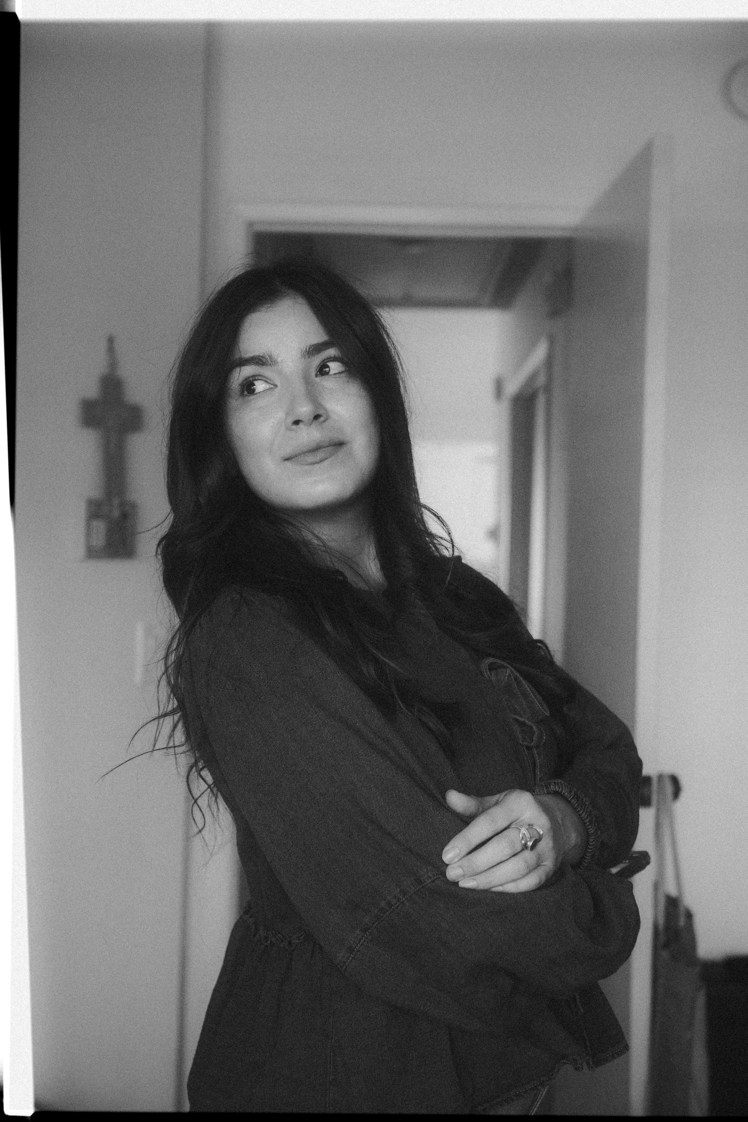 A person in a black sweater poses playfully in a series of black and white photos against a light wall.