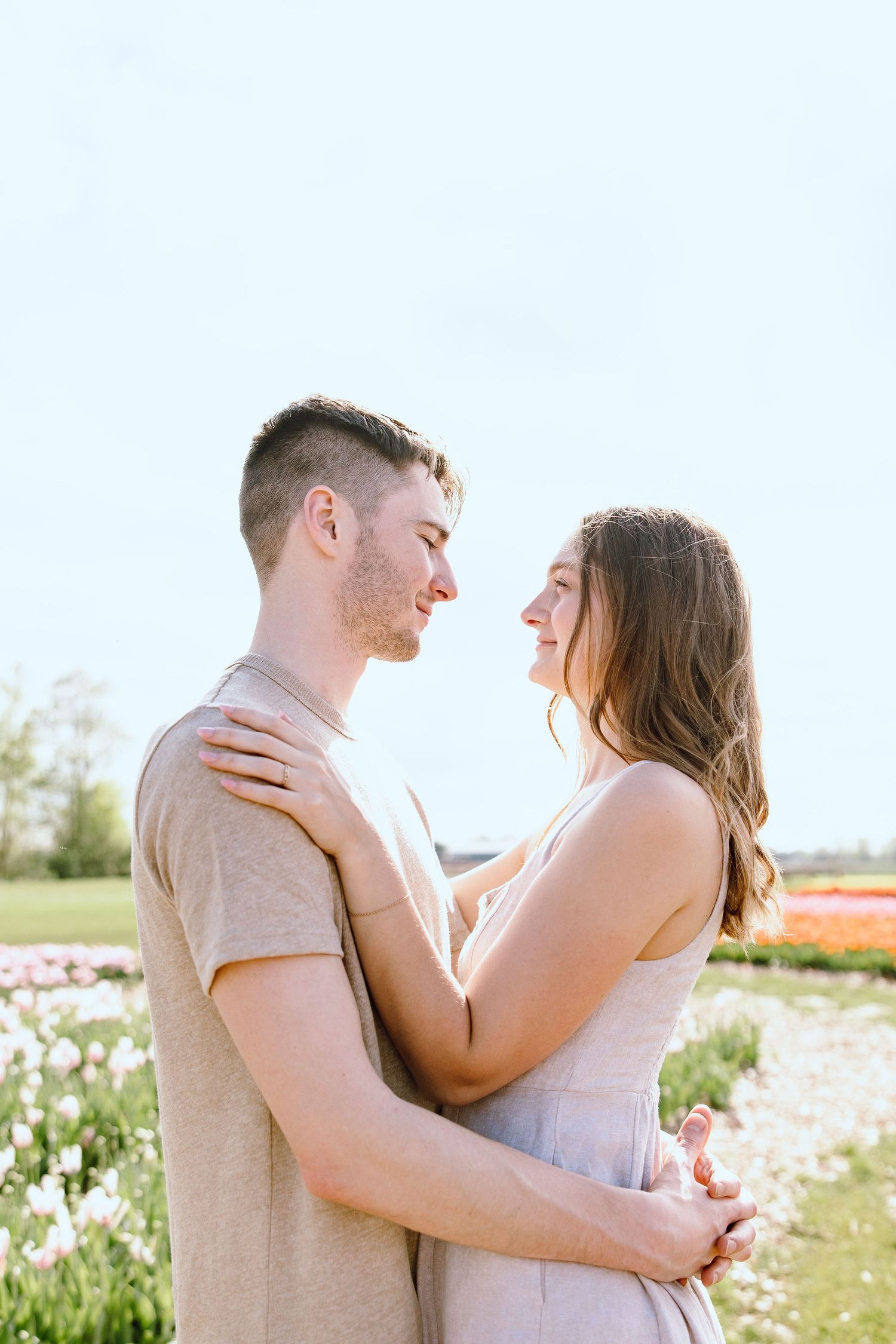 Engaged couple embracing at DeBuck's tulip field spring engagement session in Belleville, MI