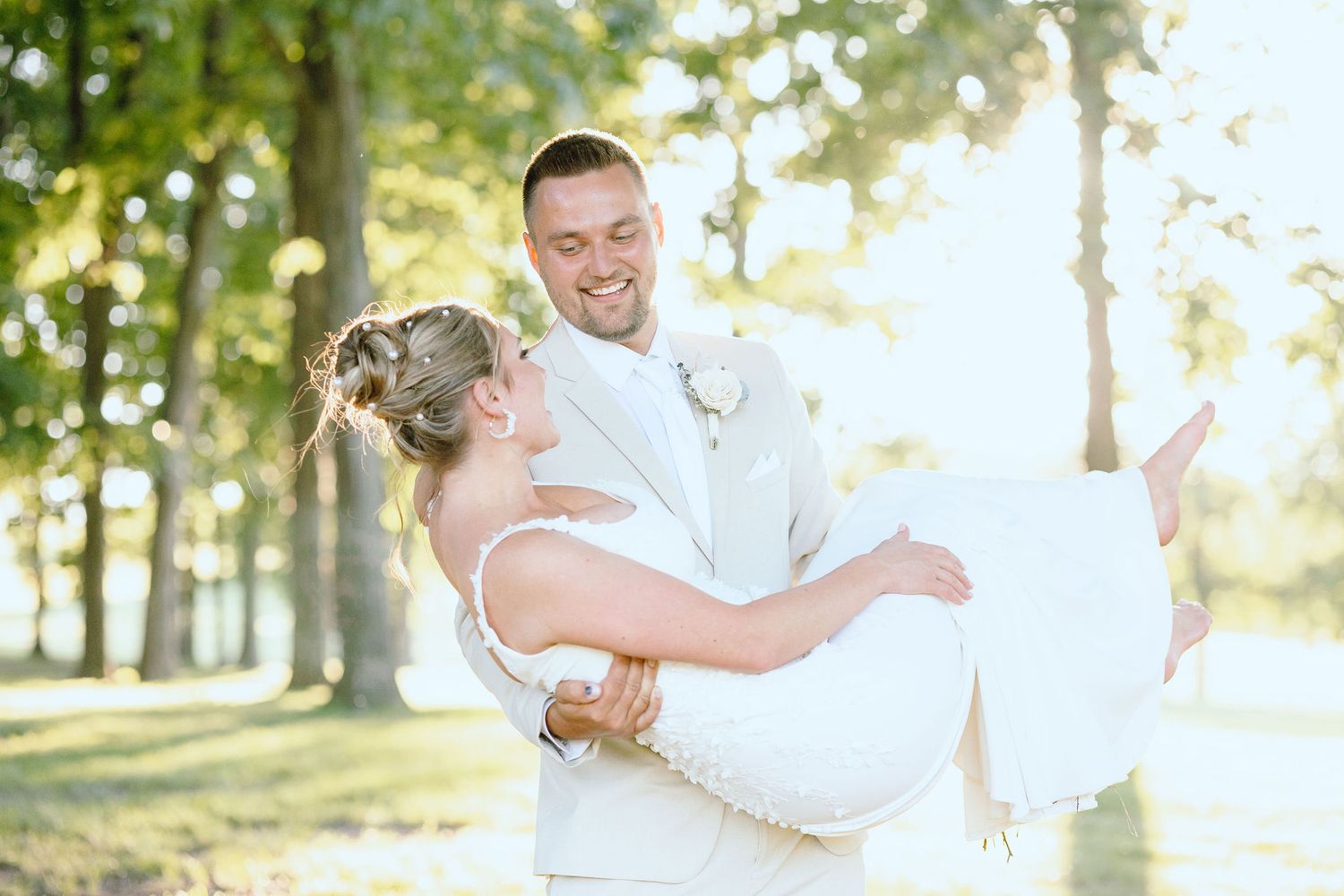 Groom carrying bride during golden hour at Lapeer Country Club forest wedding in Michigan