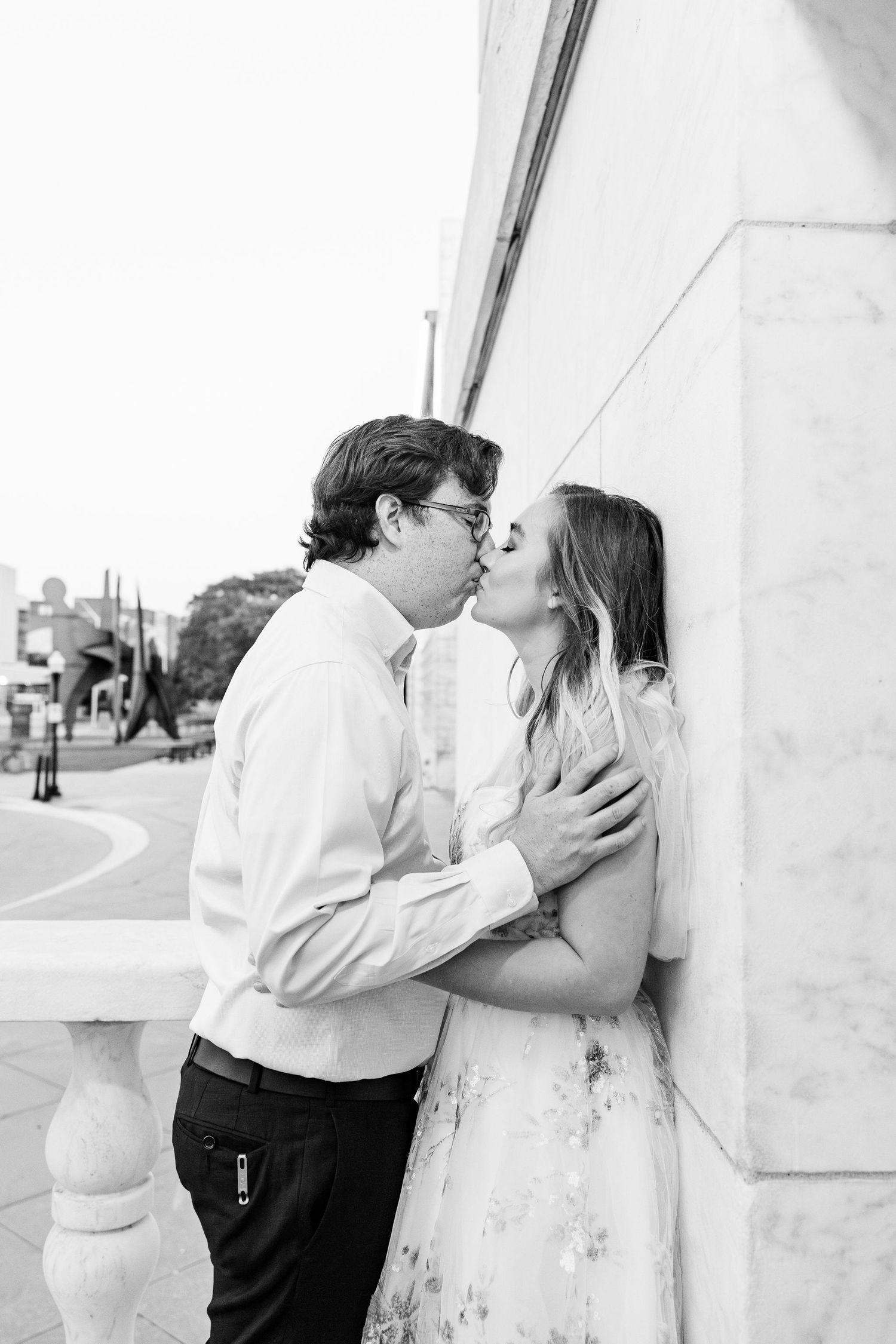 Engaged couple leaning against wall at Belle Isle summer engagement session in Detroit, MI