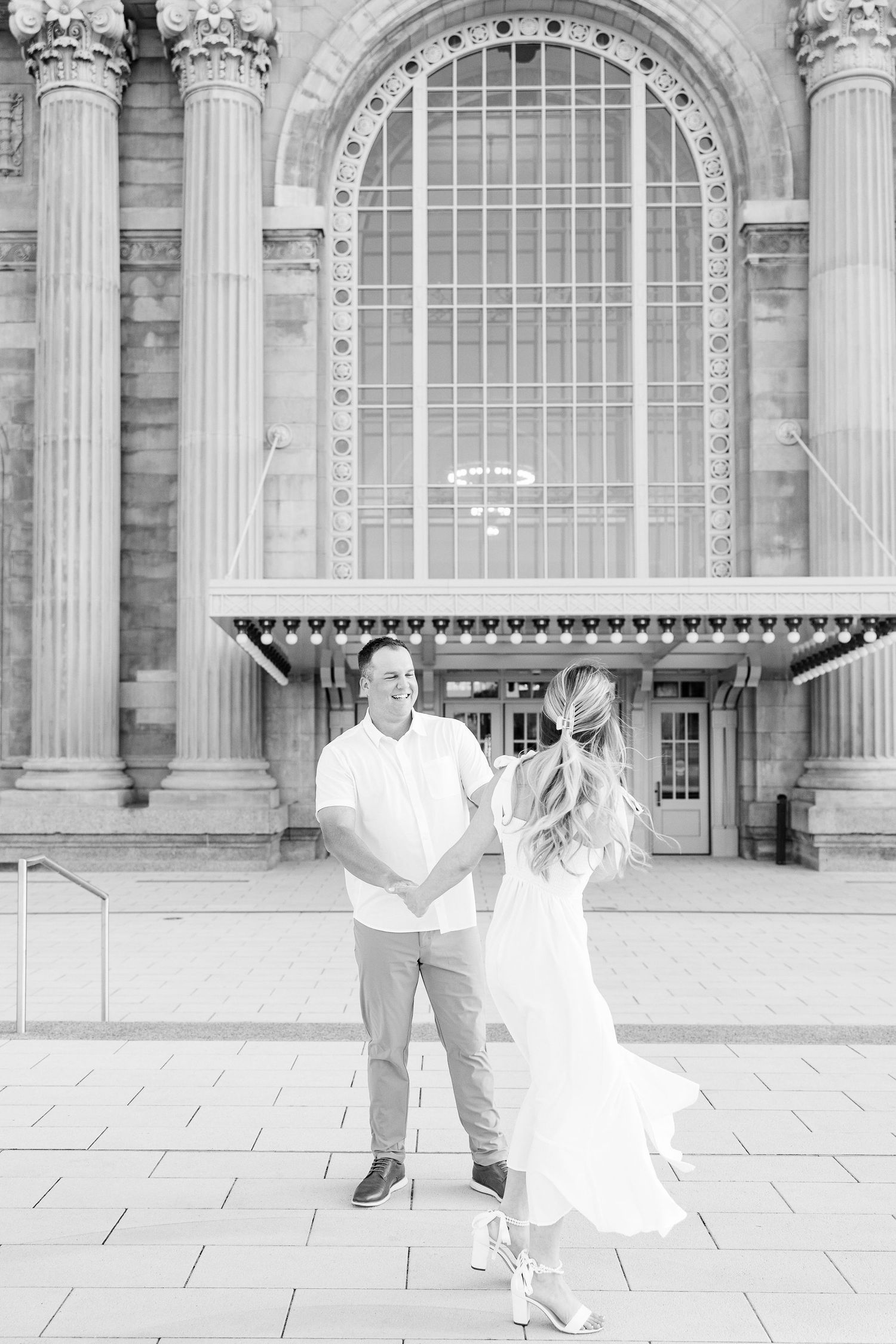 Engaged couple twirling at Michigan Central Station summer engagement session in Detroit, MI