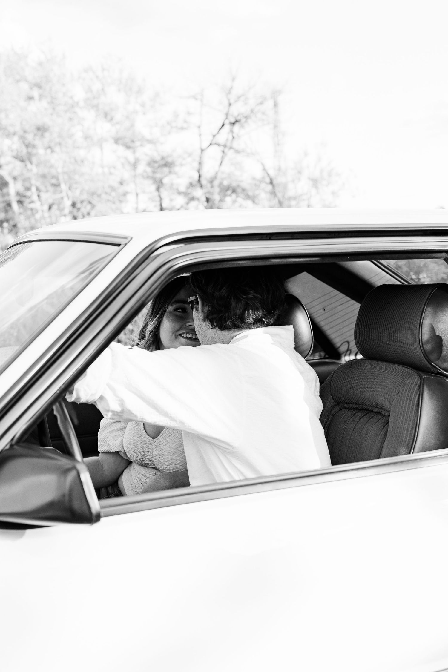 Engaged couple sitting in vintage car at Belle Isle summer engagement session in Detroit, MI