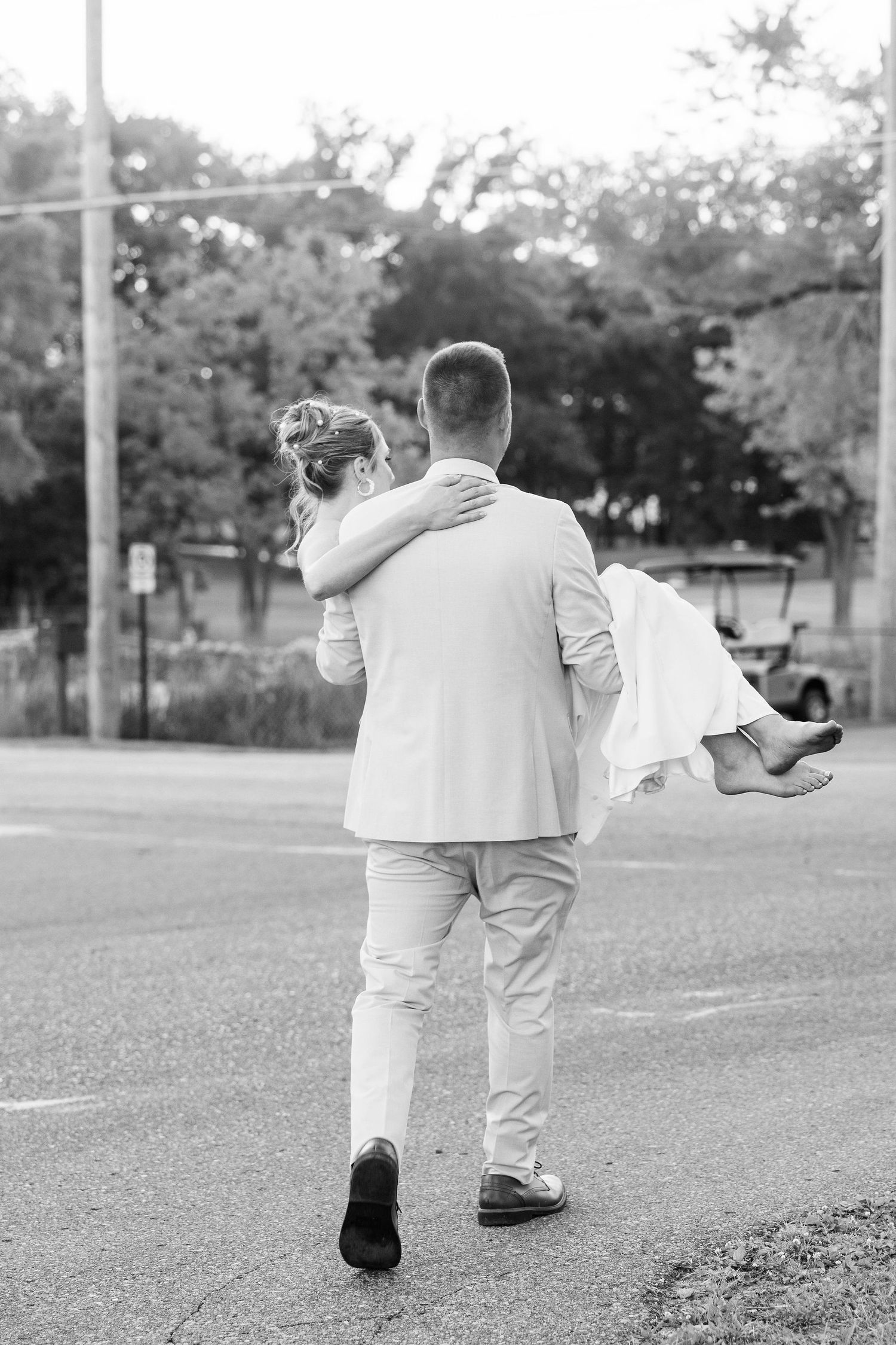 Groom carrying bride during golden hour at Lapeer Country Club forest wedding in Michigan