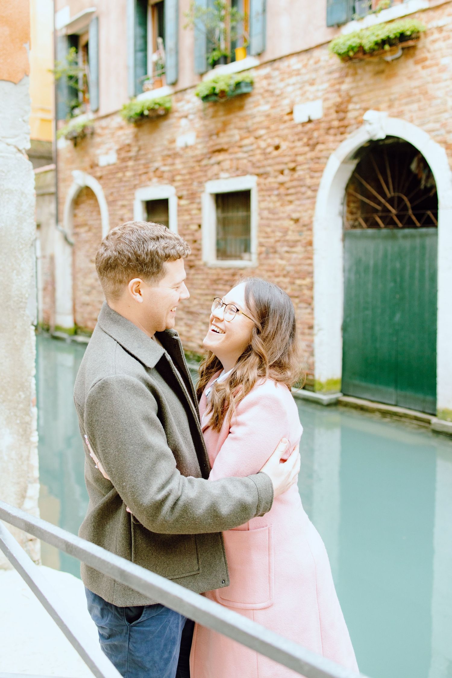 Engaged couple embracing in Venice, Italy in front of canal