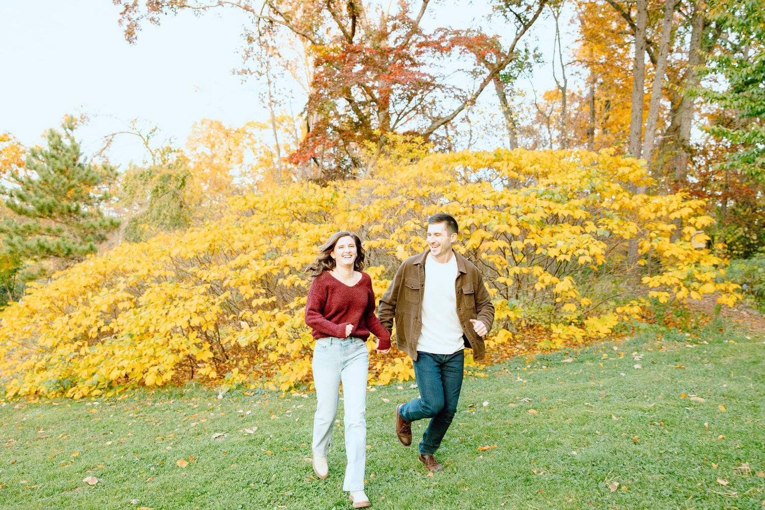 Engaged couple running and holding hands at Nichols Arboretum fall engagement session in Ann Arbor, MI