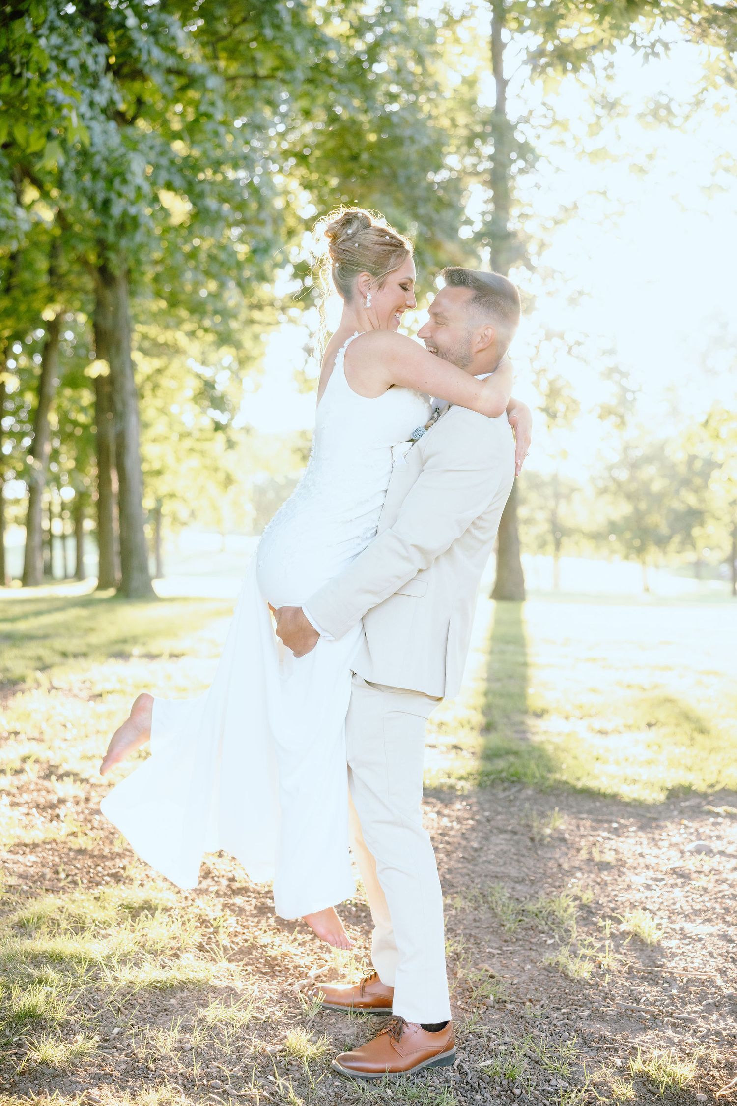 Groom carrying bride during golden hour at Lapeer Country Club forest wedding in Michigan