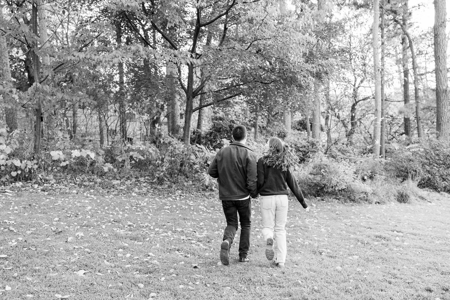 Engaged couple running and holding hands at Nichols Arboretum fall engagement session in Ann Arbor, MI