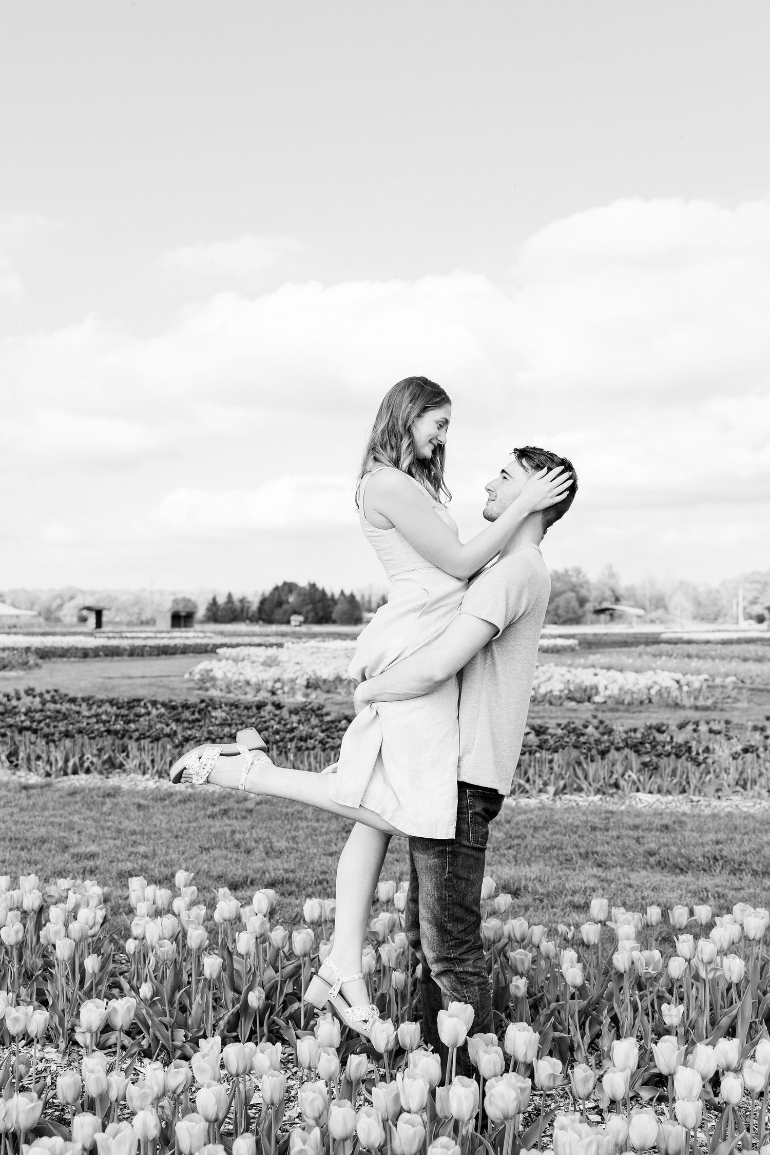 Man lifting woman at DeBuck's tulip field engagement session in Belleville, MI
Engaged couple sitting on cabin at DeBuck's tulip field