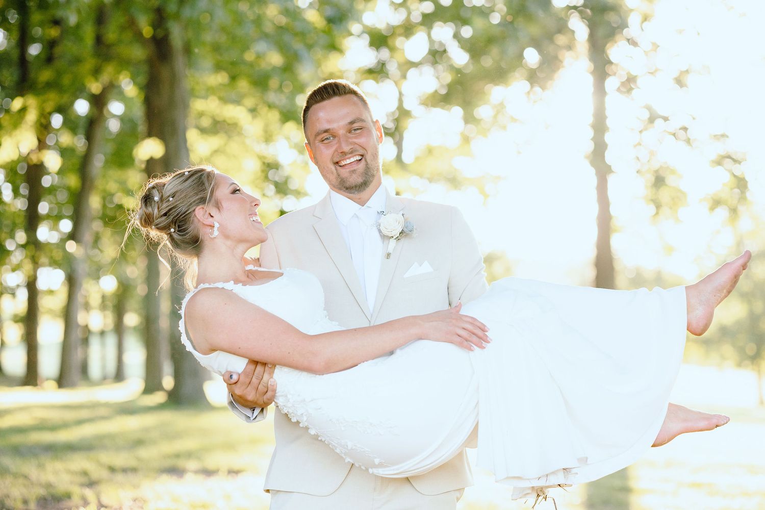 Groom carrying bride during golden hour at Lapeer Country Club forest wedding in Michigan
