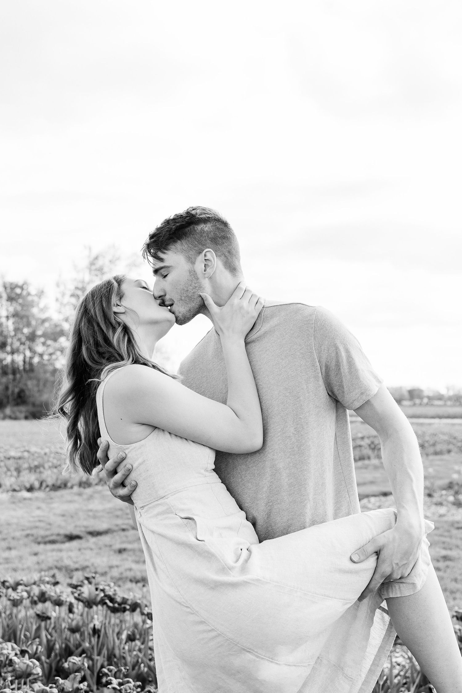 Engaged couple kissing at DeBuck's tulip field spring engagement session in Belleville, MI