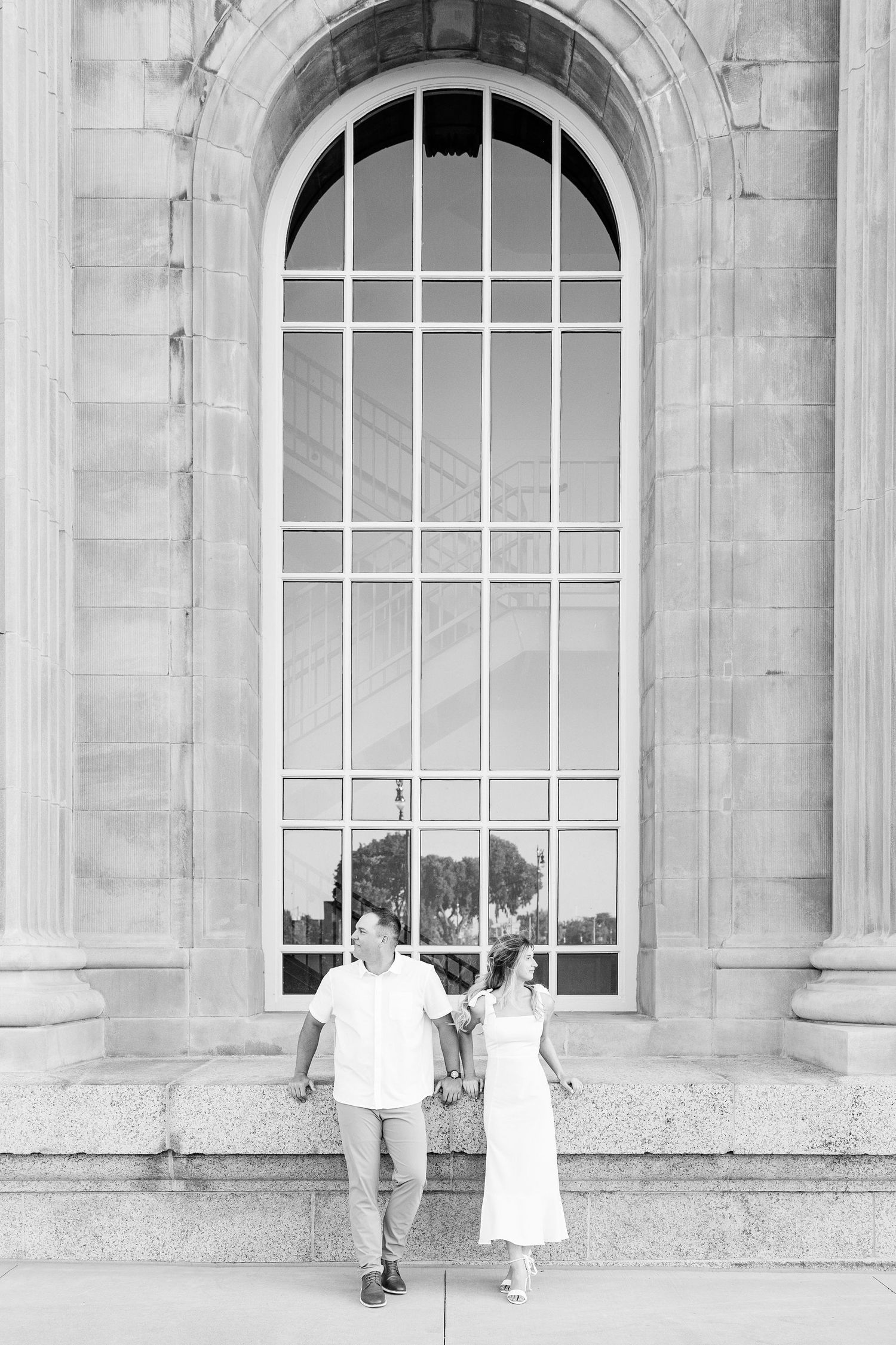 Engaged couple sitting at Michigan Central Station summer engagement session in Detroit, MI