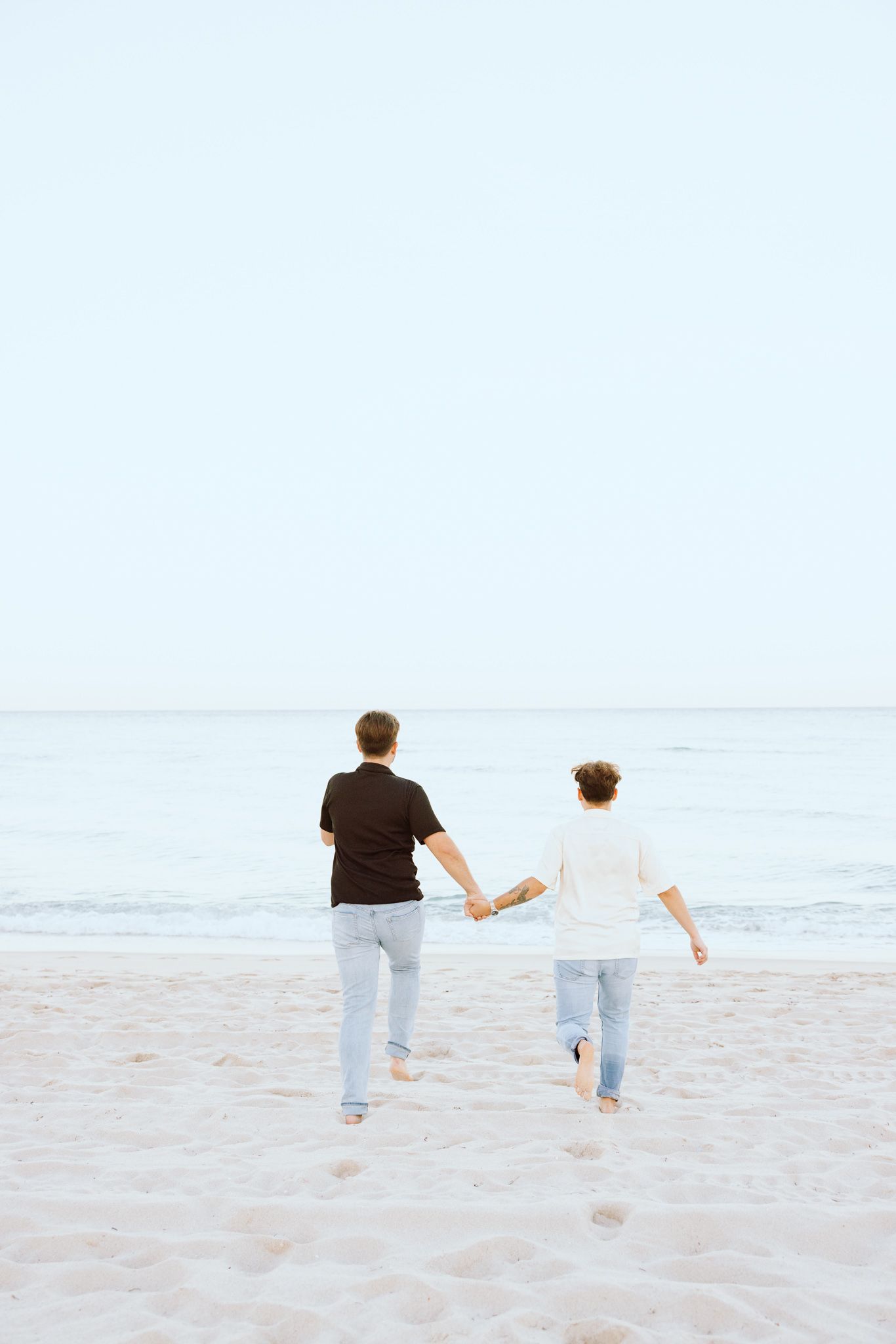 LGBTQ+ couple running and holding hands on North Miami Beach in Florida