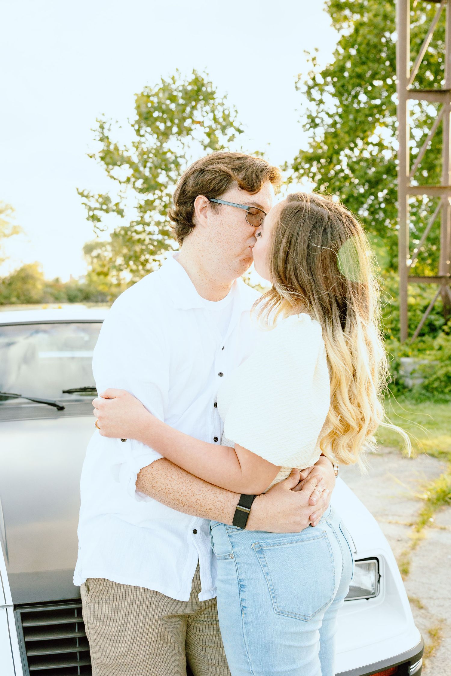Engaged couple kissing against vintage car at Belle Isle summer engagement session in Detroit, MI